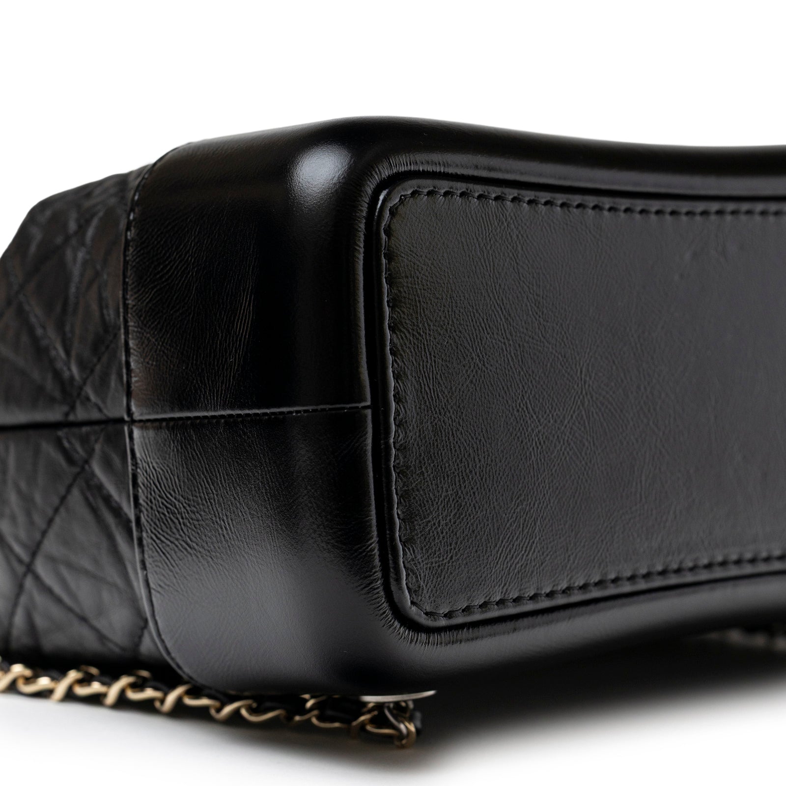 Close-up of the bottom corner showing smooth black aged calfskin and mixed metal hardware on the Chanel Small Gabrielle Backpack Black Aged Calfskin Mixed Metal Hardware