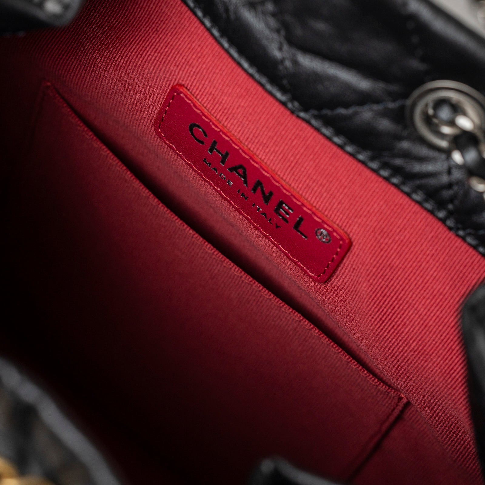 Close-up interior view of Chanel Small Gabrielle Backpack Black Aged Calfskin Mixed Metal Hardware showing red lining and logo label