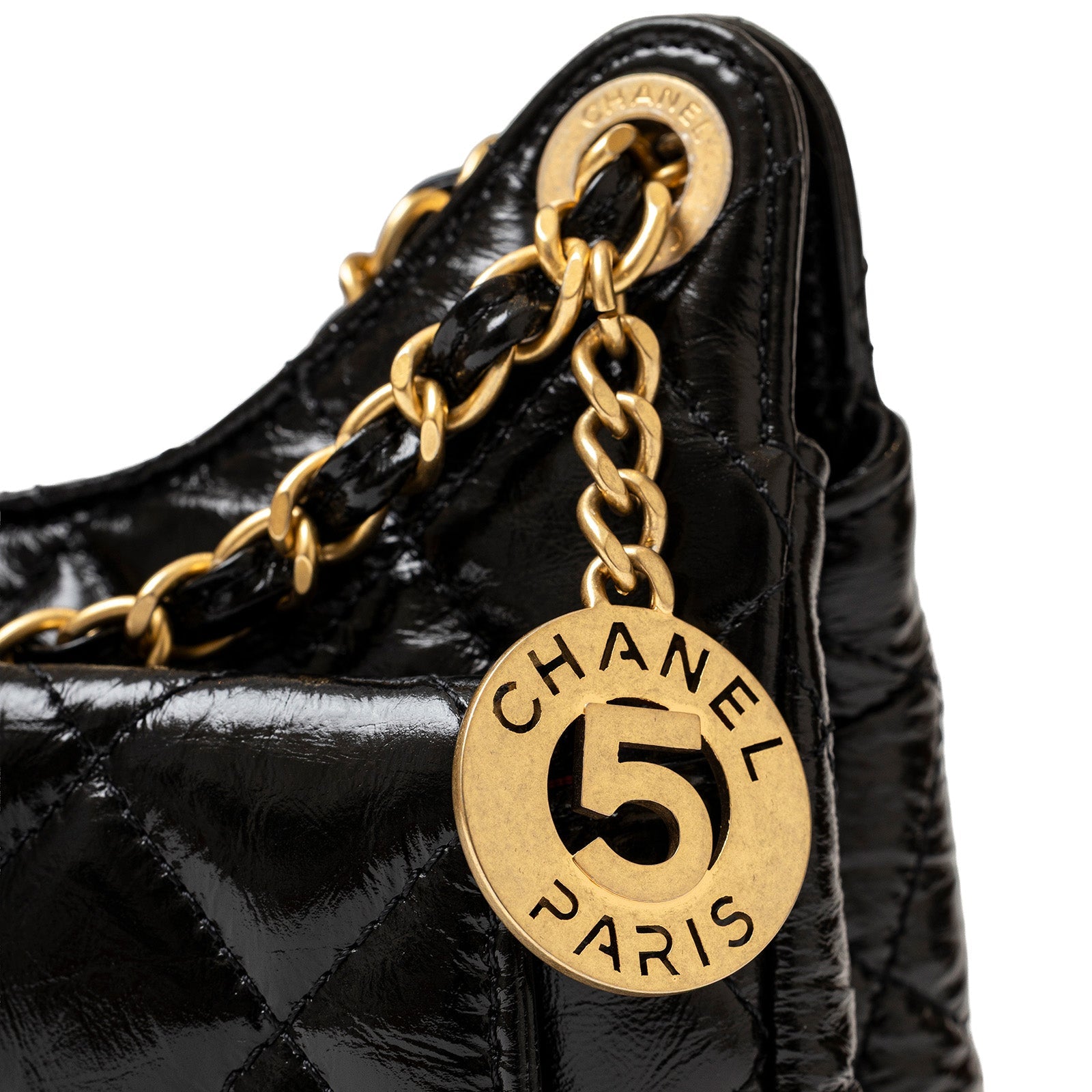 Close-up of gold Chanel Paris charm and chain on black Chanel Wavy CC Hobo Small Shiny Quilted Calf Gold Hardware