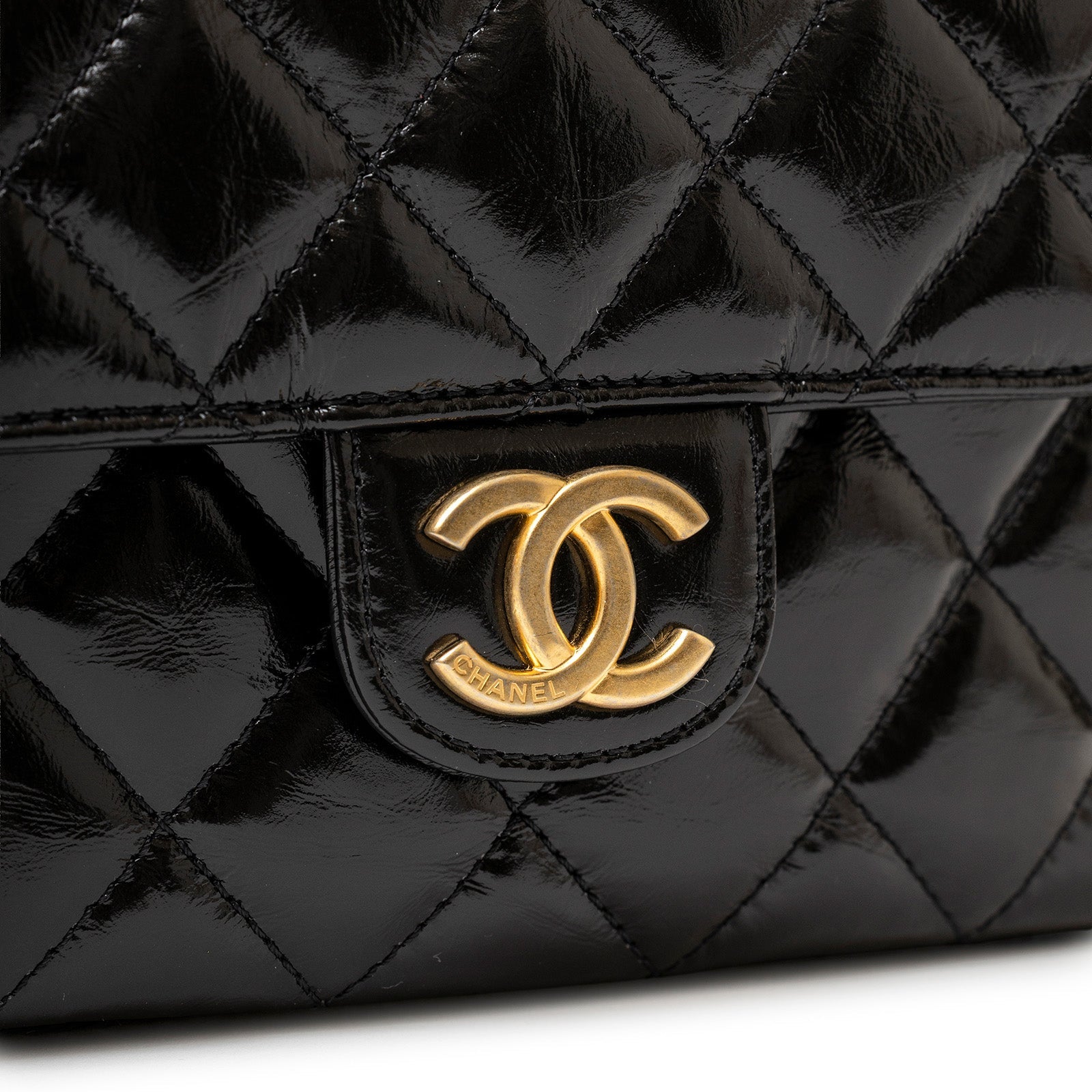 Close-up of gold CC hardware on black shiny quilted leather for Chanel Wavy CC Hobo Small Shiny Quilted Calf Gold Hardware