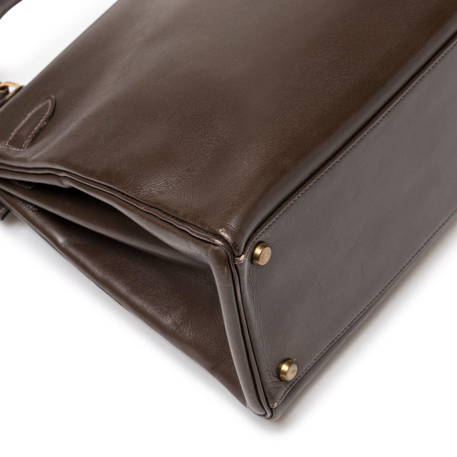 Close-up of base corner on Hermès 1974 Vintage Kelly 32 Marron Foncé Box Gold Hardware showing smooth leather and gold feet