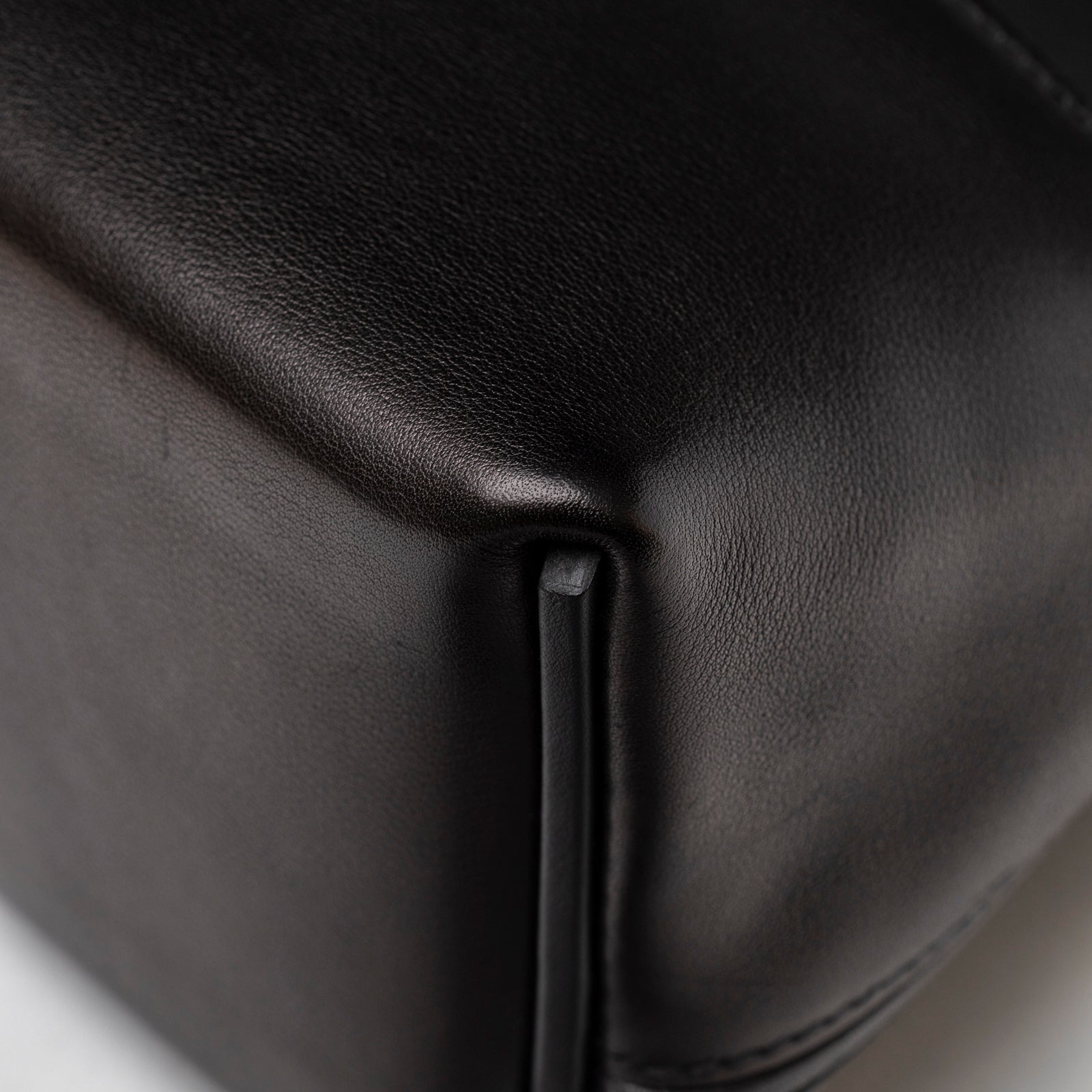 Close-up of smooth black leather base corner and piping details on Hermès 24/24 21 Touch Black Lizard Volupto Gold Hardware