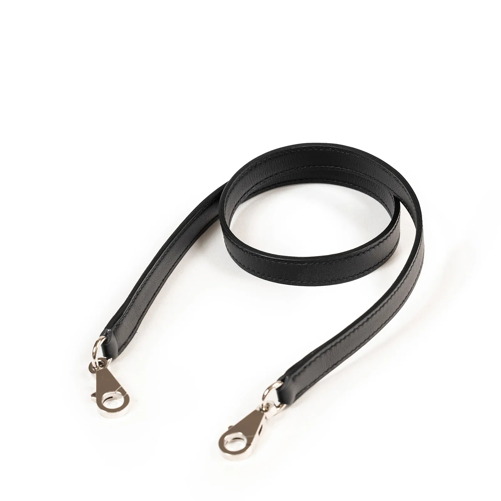 Close-up of black Taurillon Maurice leather shoulder strap with polished palladium clasps on white background