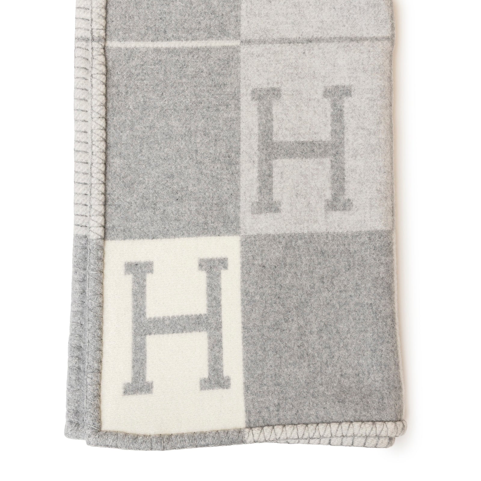 Soft folded Hermès Avalon Throw Blanket Ecru Gris Clair featuring elegant block pattern with subtle H monogram details.
