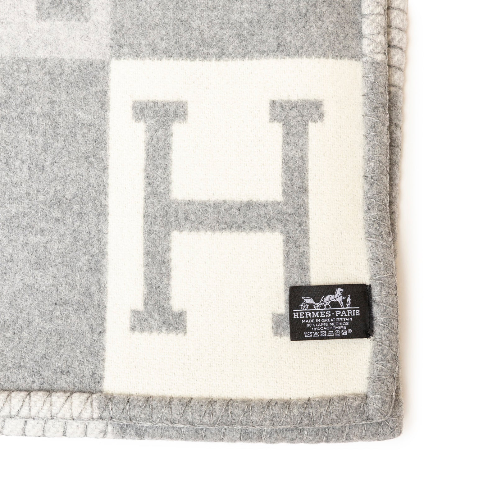 Close-up of the corner of Hermès Avalon Throw Blanket Ecru Gris Clair showing soft woven texture and label detail
