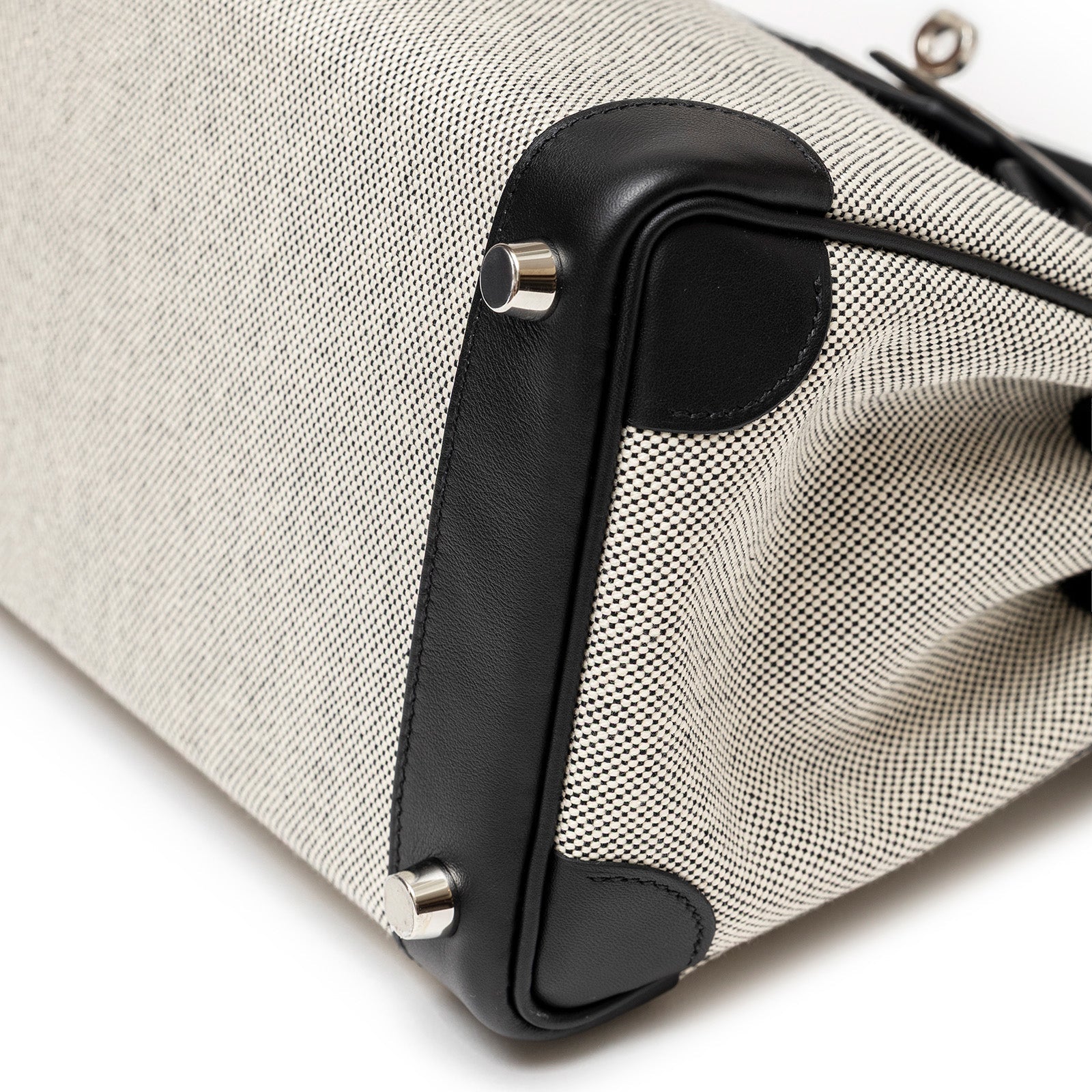 Close-up of bottom corner and palladium hardware of Hermès Birkin 25 Black Swift/Ecru Toile H Canvas by Hermès