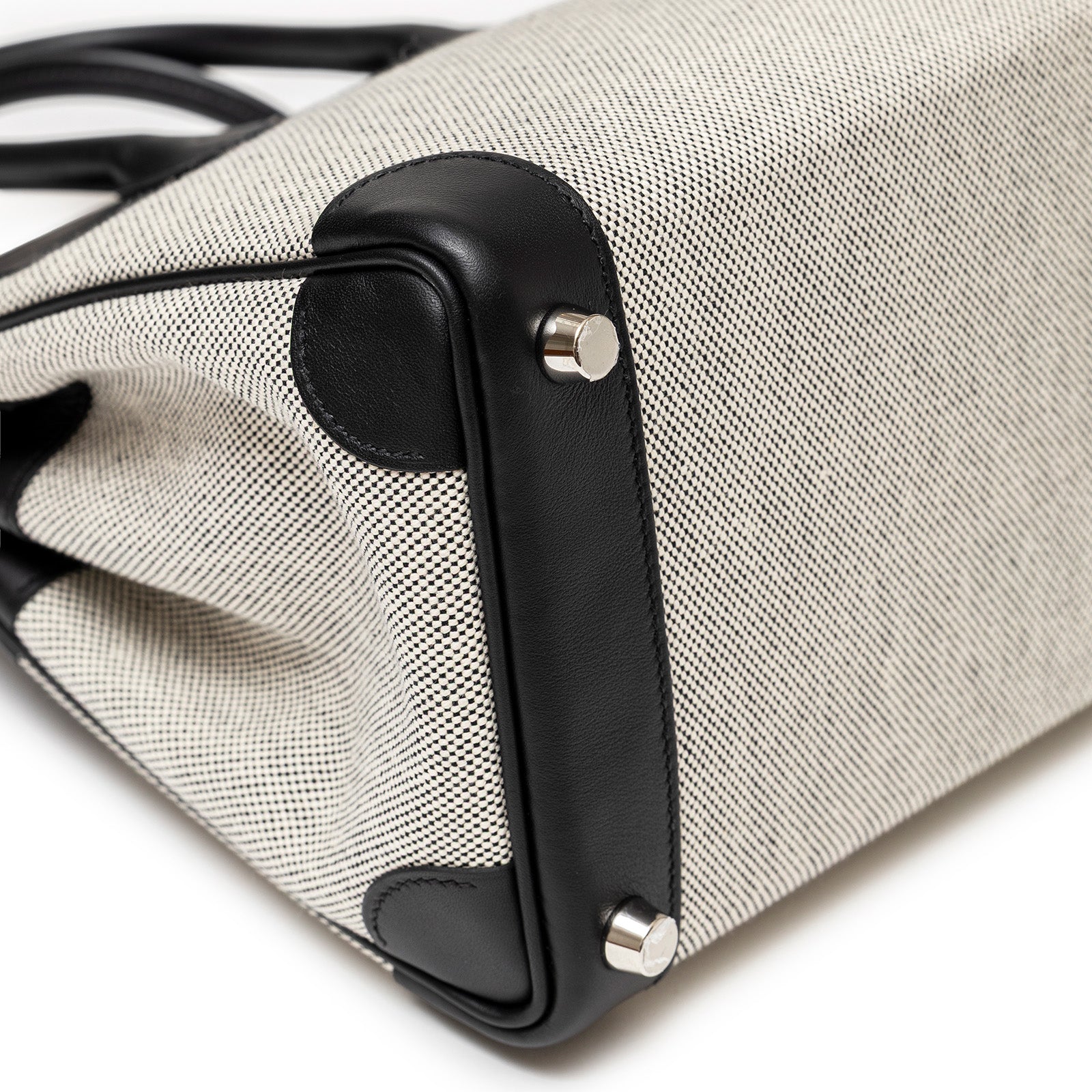 Close-up of the bottom corner with palladium hardware on Hermès Birkin 25 Black Swift/Ecru Toile H Canvas by Hermès