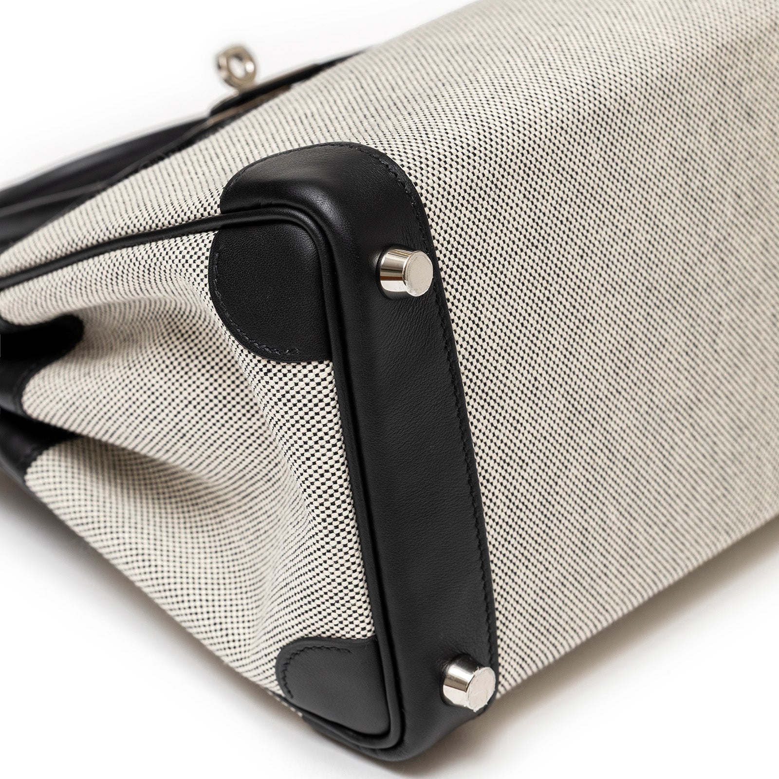 Close-up bottom view of Hermès Birkin 25 Black Swift/Ecru Toile H Canvas Palladium hardware by Hermès luxury handbags