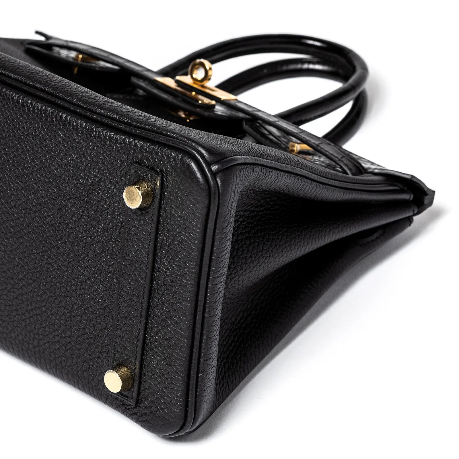 Close-up angled view of Hermès Birkin 25 in black Togo leather showing bottom with gold hardware feet.
