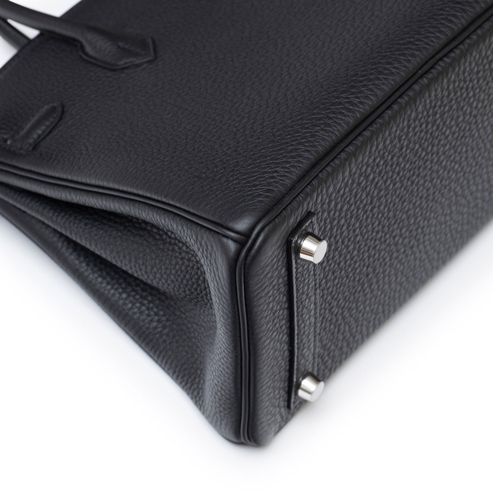 Close-up angled shot of Hermès Birkin 25 Black Togo Palladium Hardware showing textured leather and metal feet details