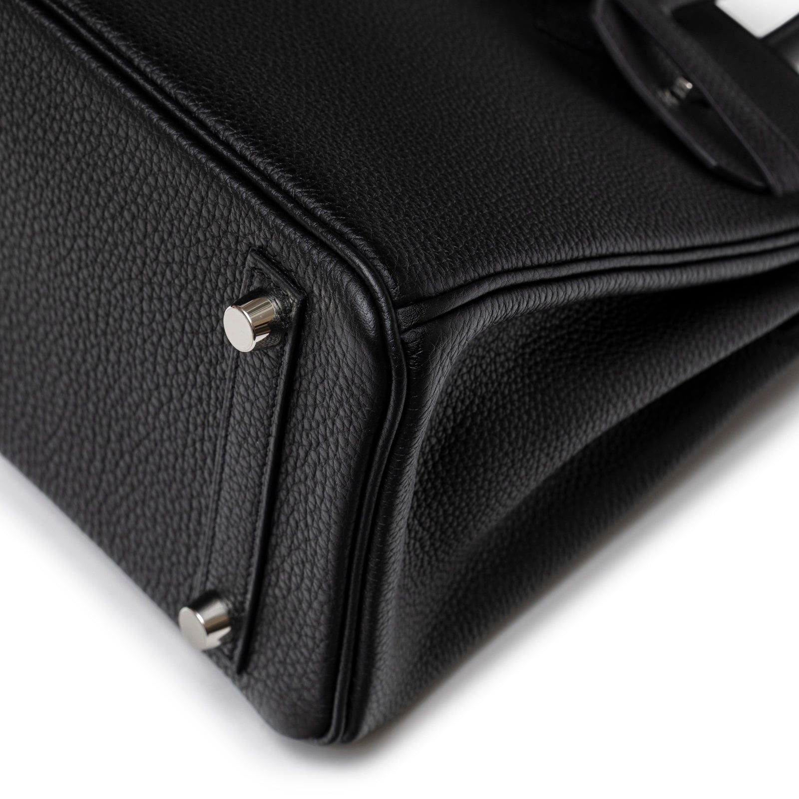 Close-up bottom corner of Hermès Birkin 25 Black Togo Palladium Hardware highlighting textured leather and metal feet