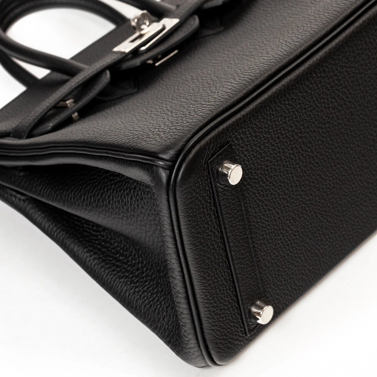 Close-up of the black Togo leather Hermès Birkin 25 bottom corner with palladium hardware feet and texture details.