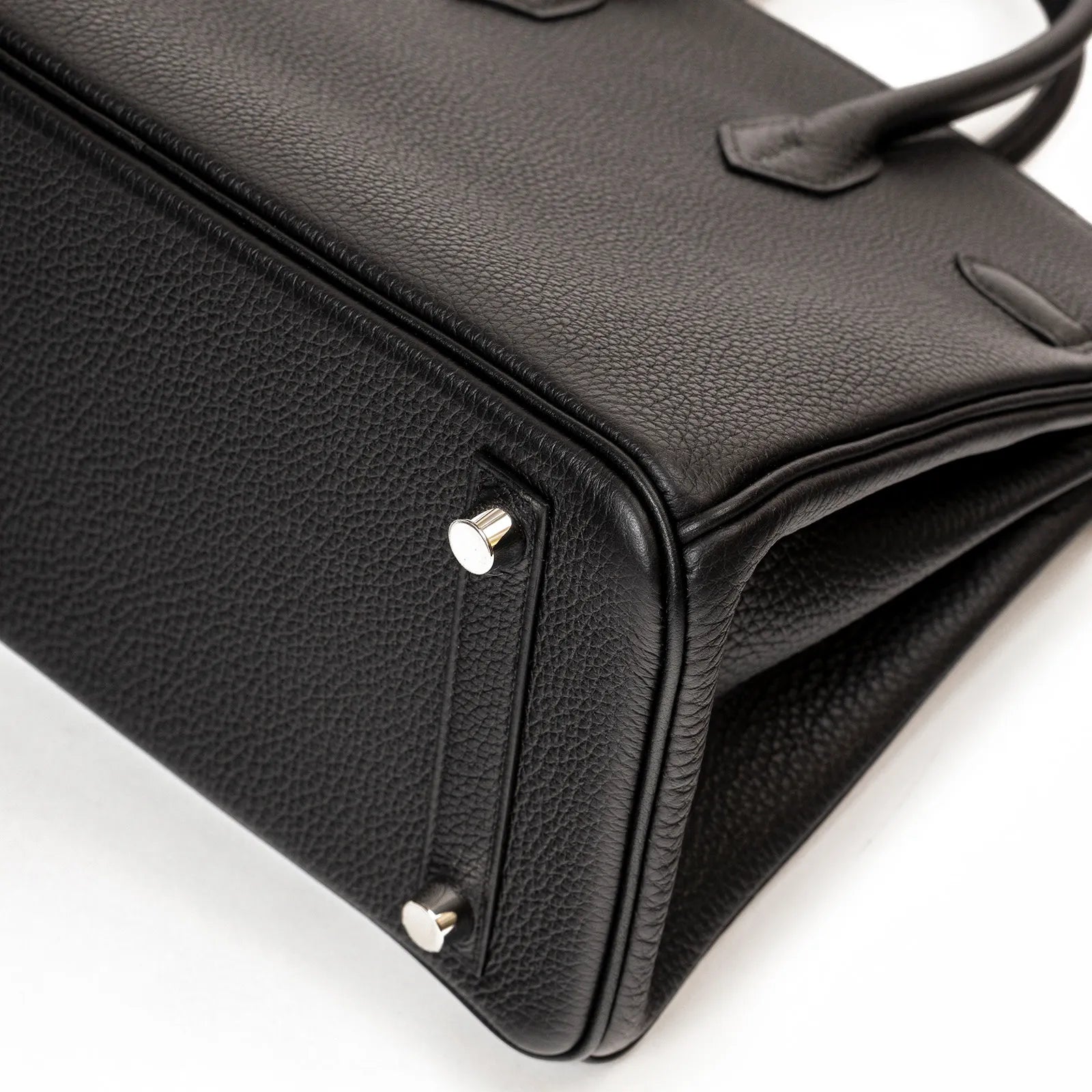 Close-up of black Togo leather base with protective palladium metal feet on Hermès Birkin 25 handbag