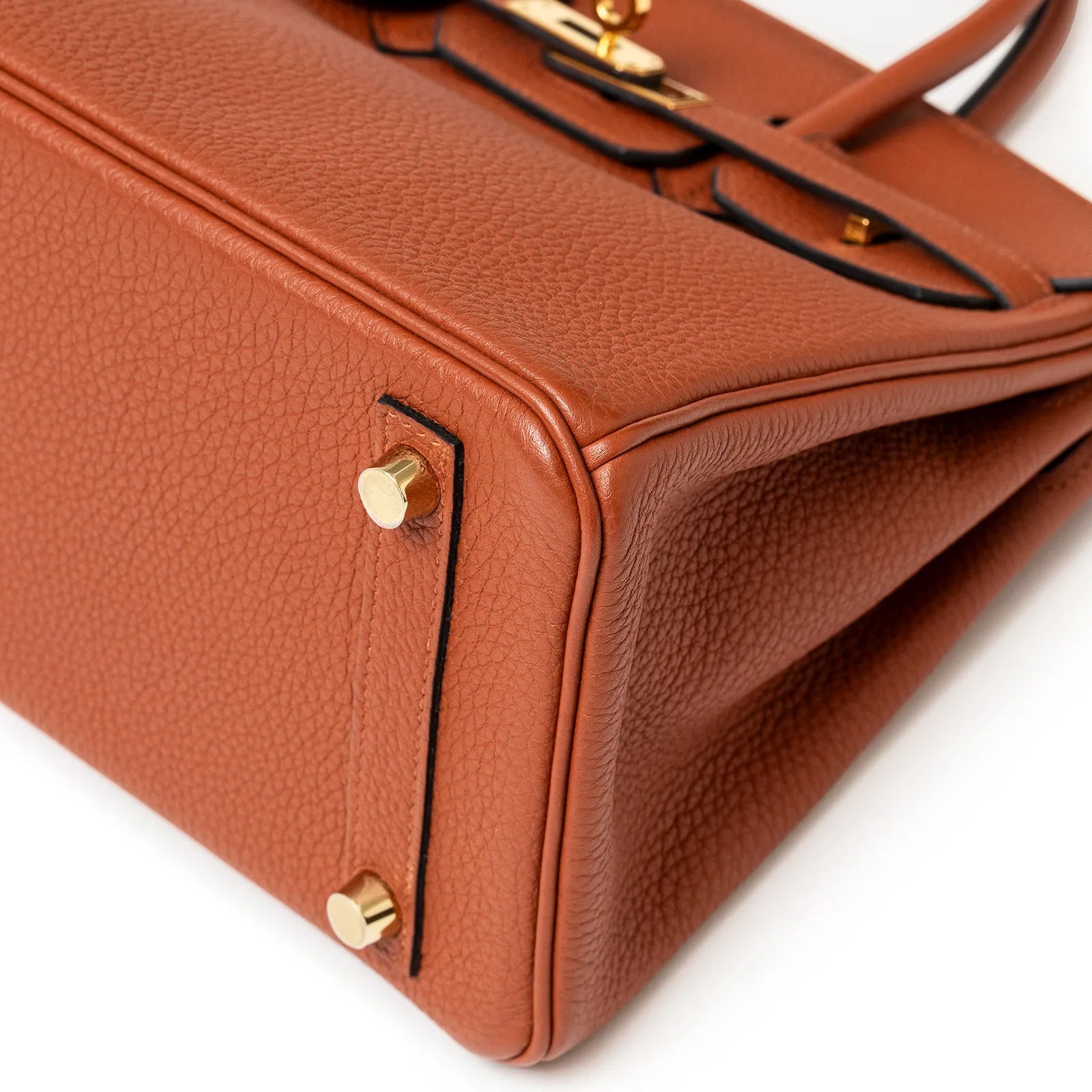 Close-up angled shot of the copper togo leather bag corner showing gold hardware feet and detailed texture