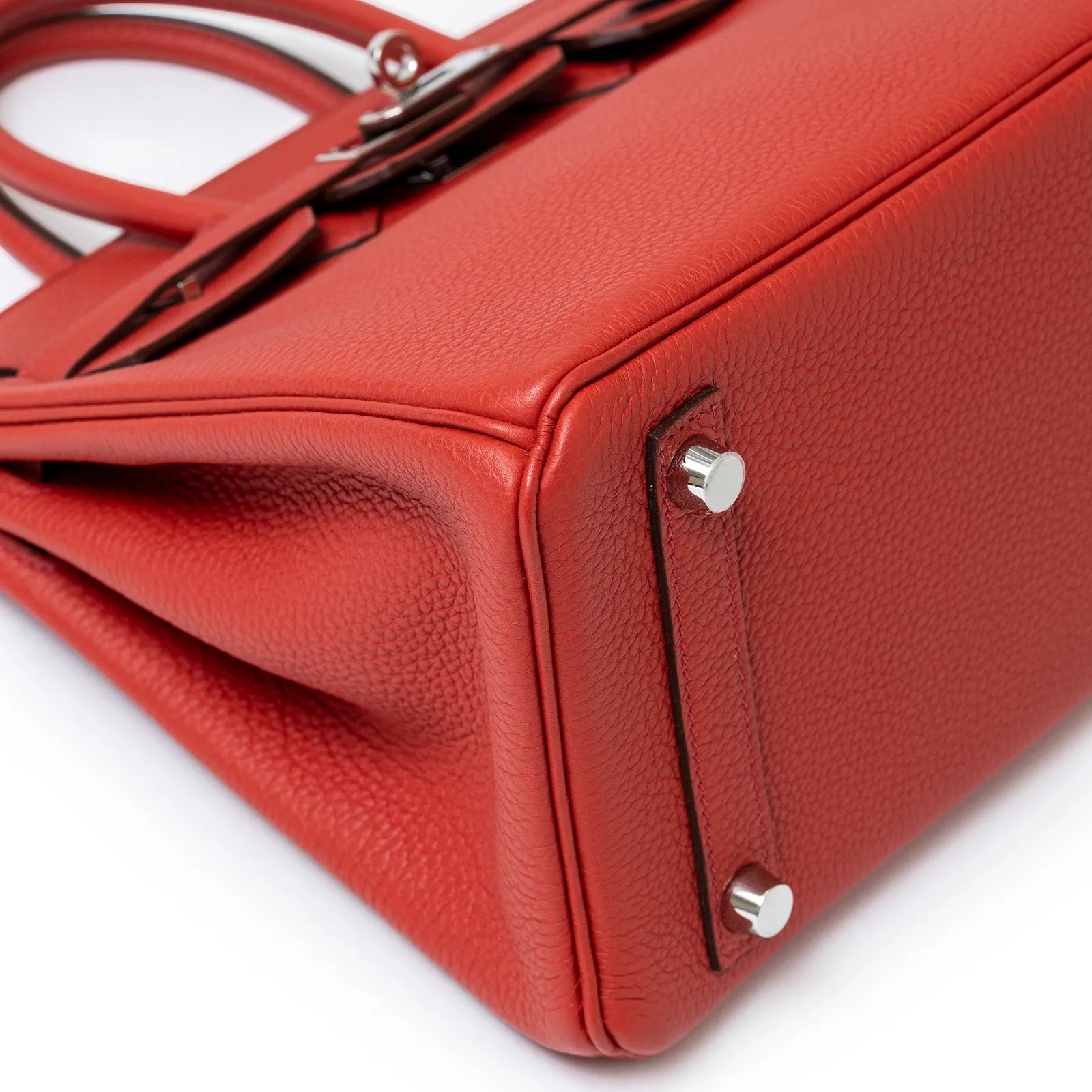 Close-up of bottom corner and palladium hardware on Hermès Birkin 25 Geranium Togo Palladium Hardware bag.