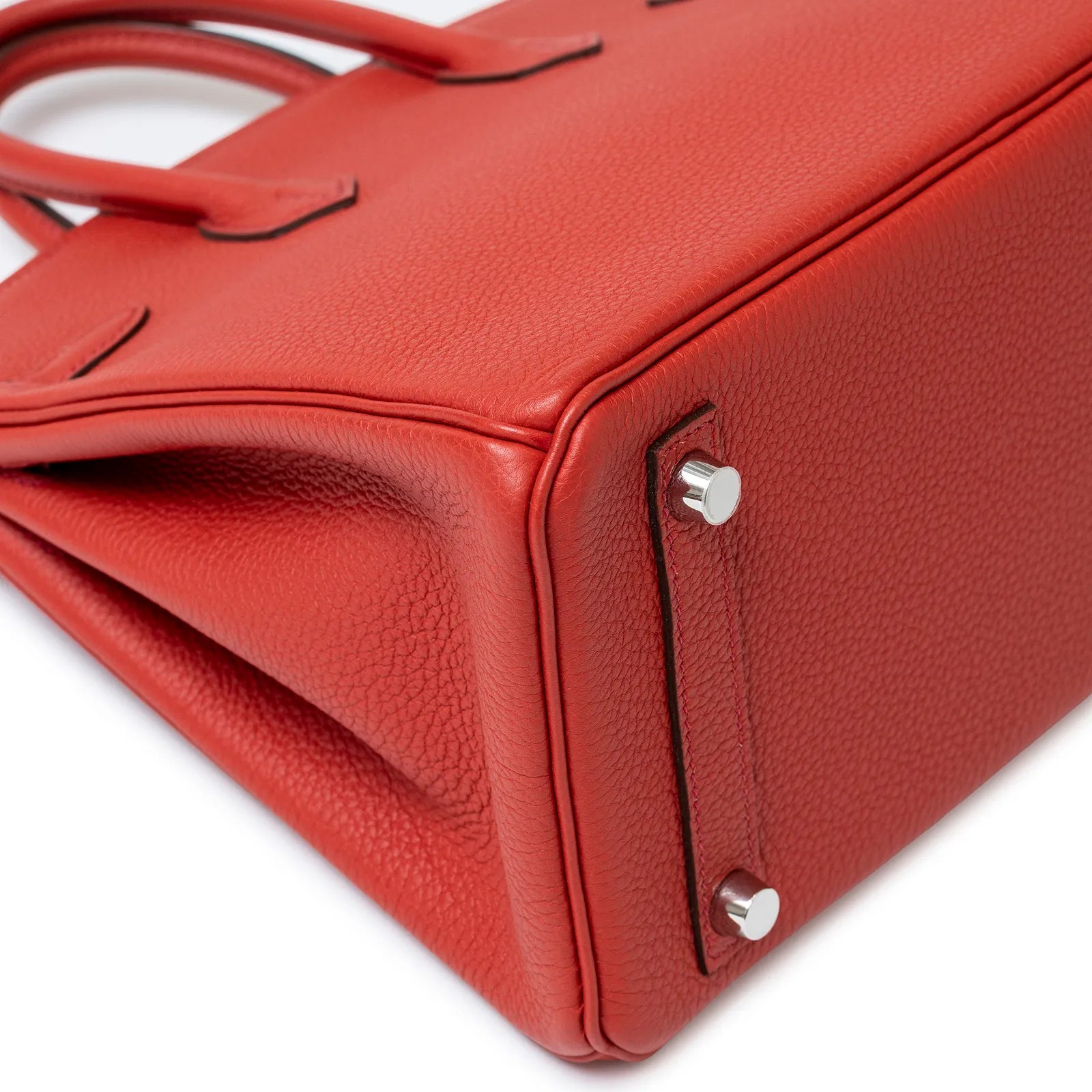 Close-up of bottom corner on Hermès Birkin 25 Geranium Togo leather with palladium hardware feet.