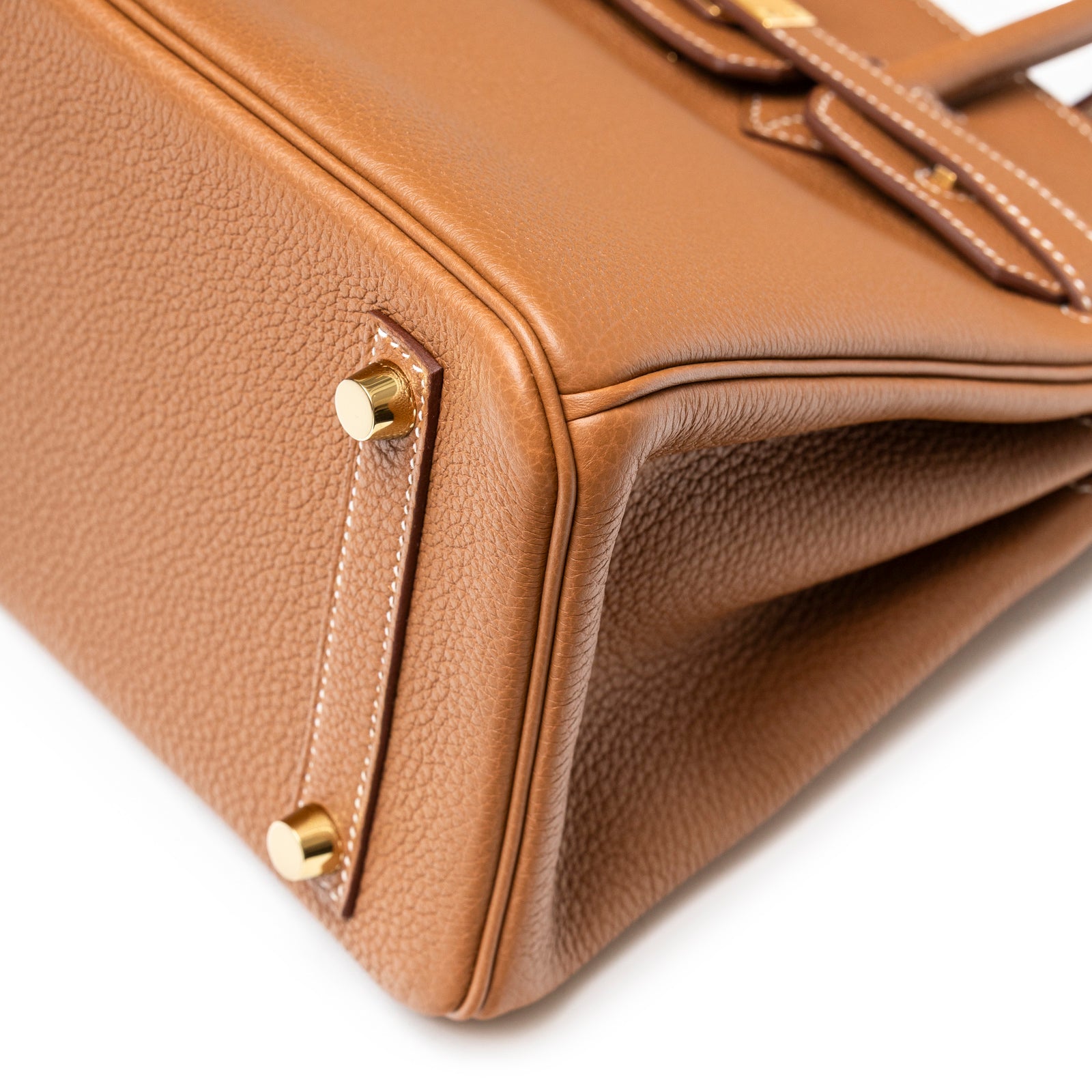 Close-up angled shot of bottom corner showing gold hardware and textured gold togo leather on Hermès Birkin 25 Gold Togo Gold Hardware.