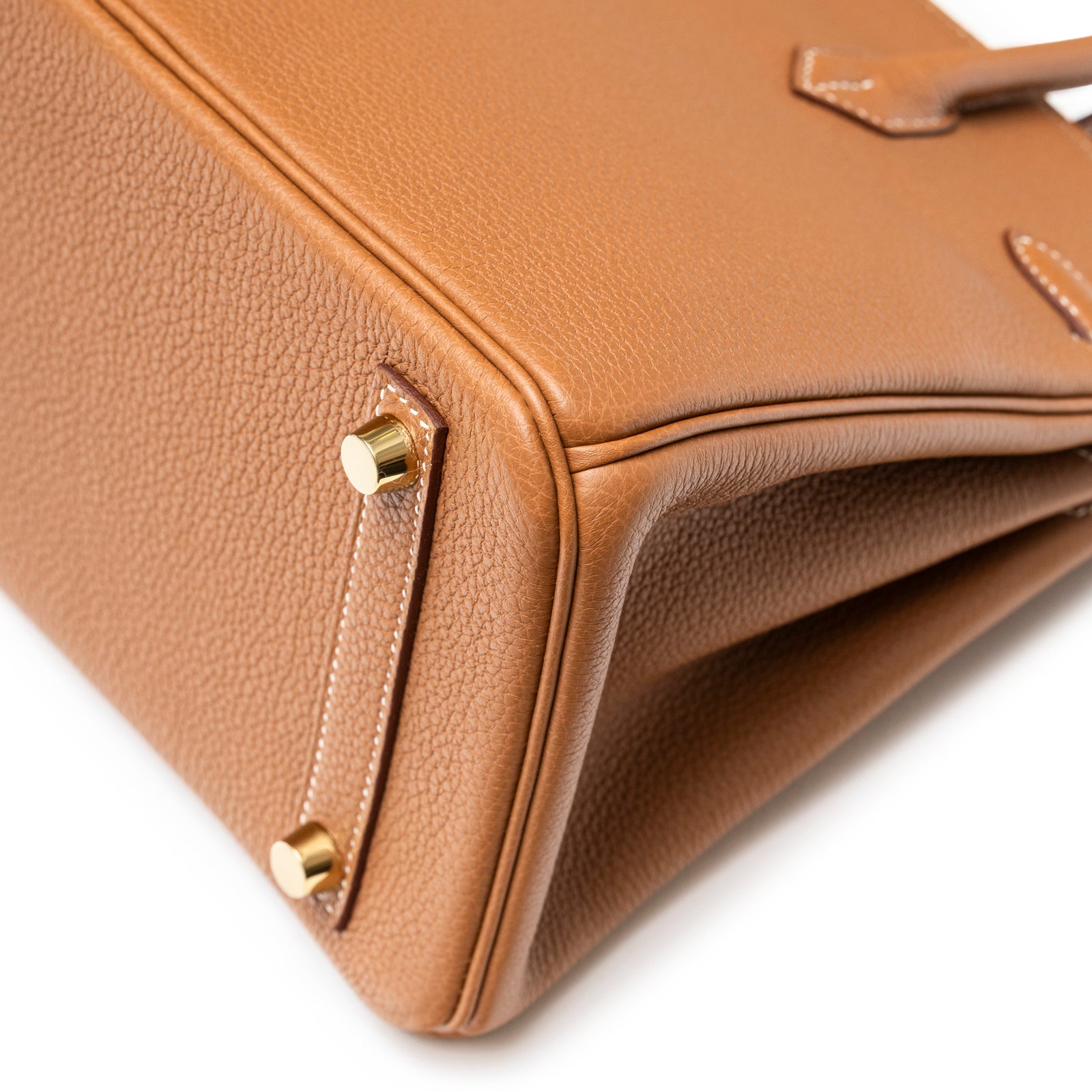 Close-up of bottom corner showing textured gold togo leather and gold hardware on Hermès Birkin 25 Gold Togo Gold Hardware.