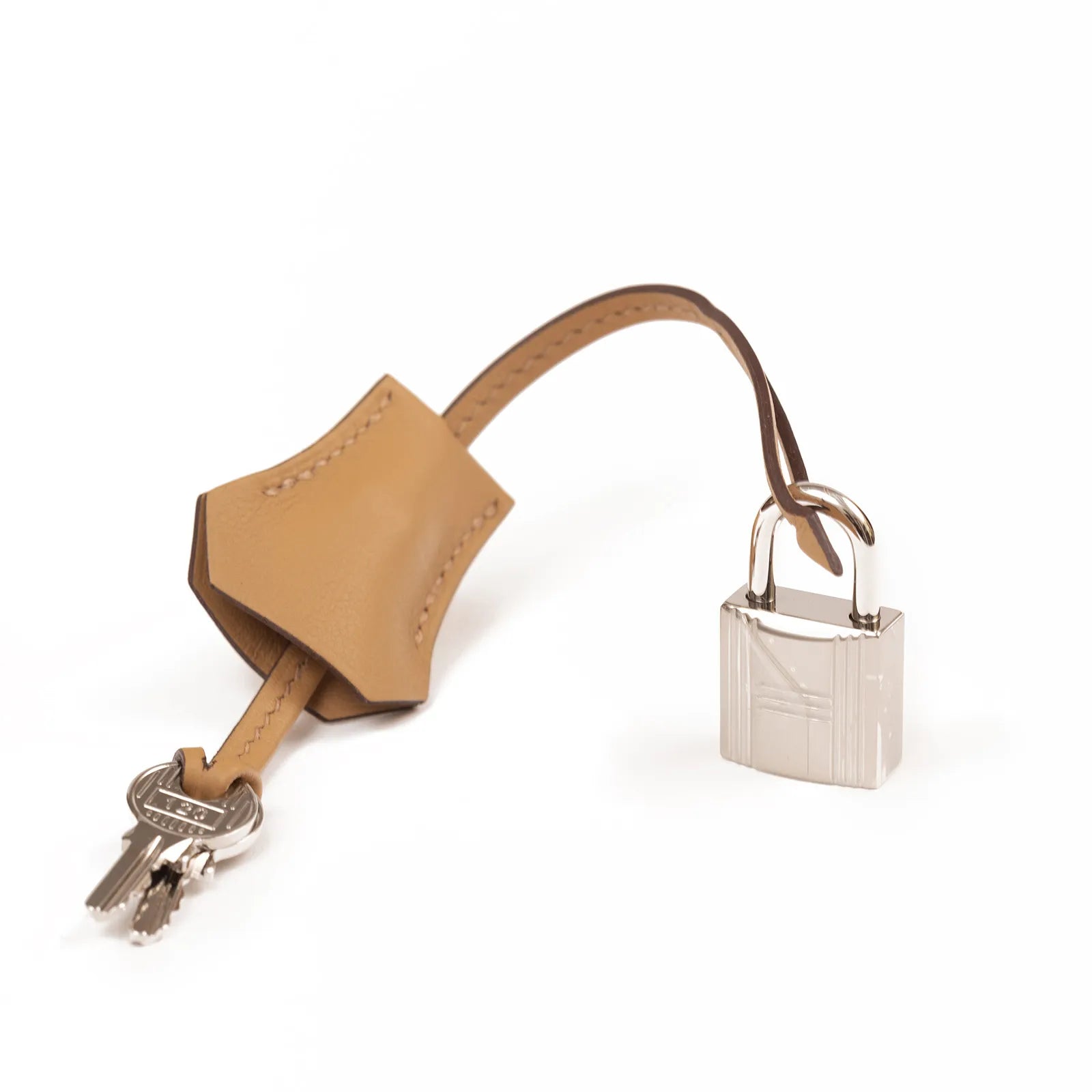 Close-up of biscuit leather clochette with two keys and palladium padlock on white background