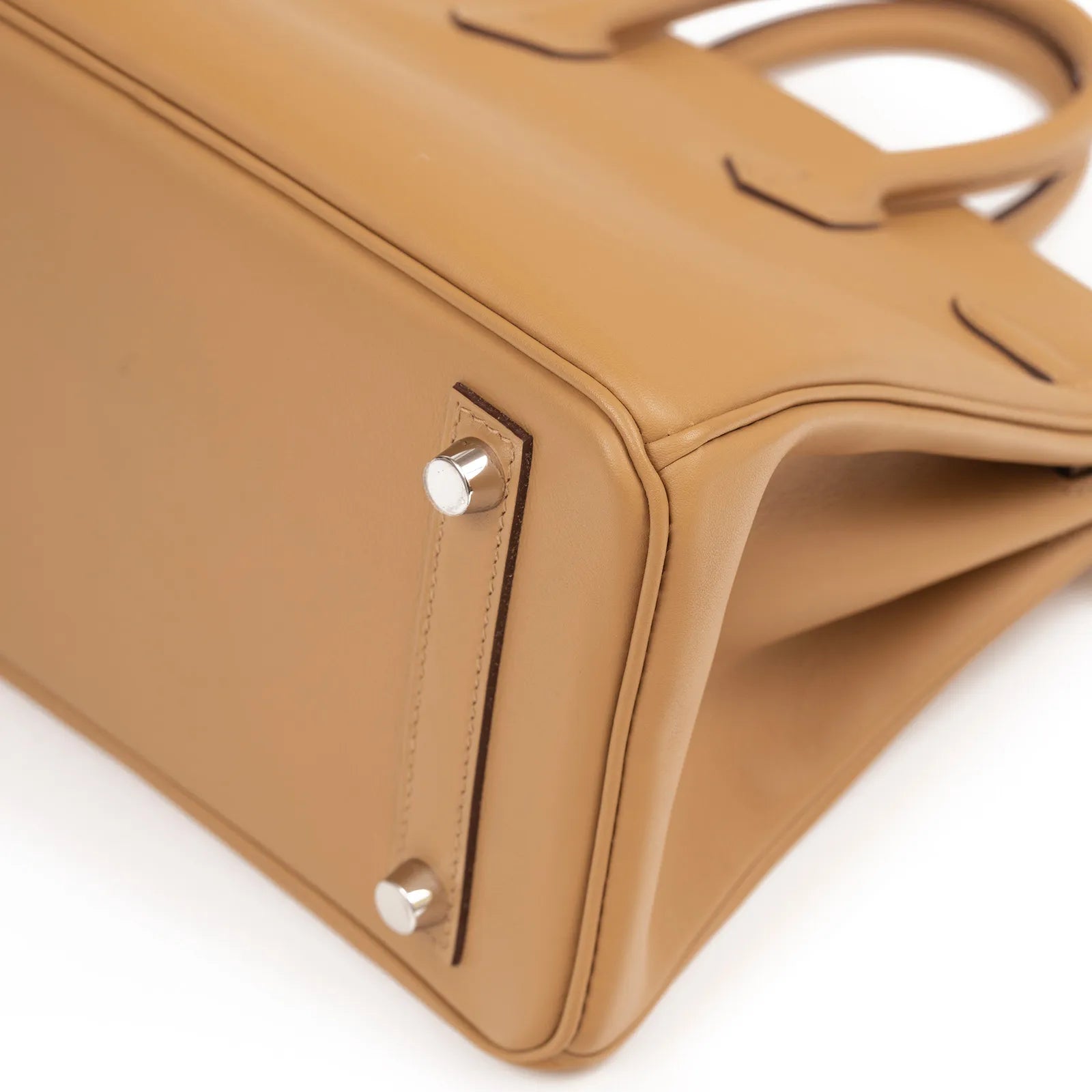 Close-up angled view of biscuit leather bottom with silver feet hardware on Birkin 25 In and Out bag