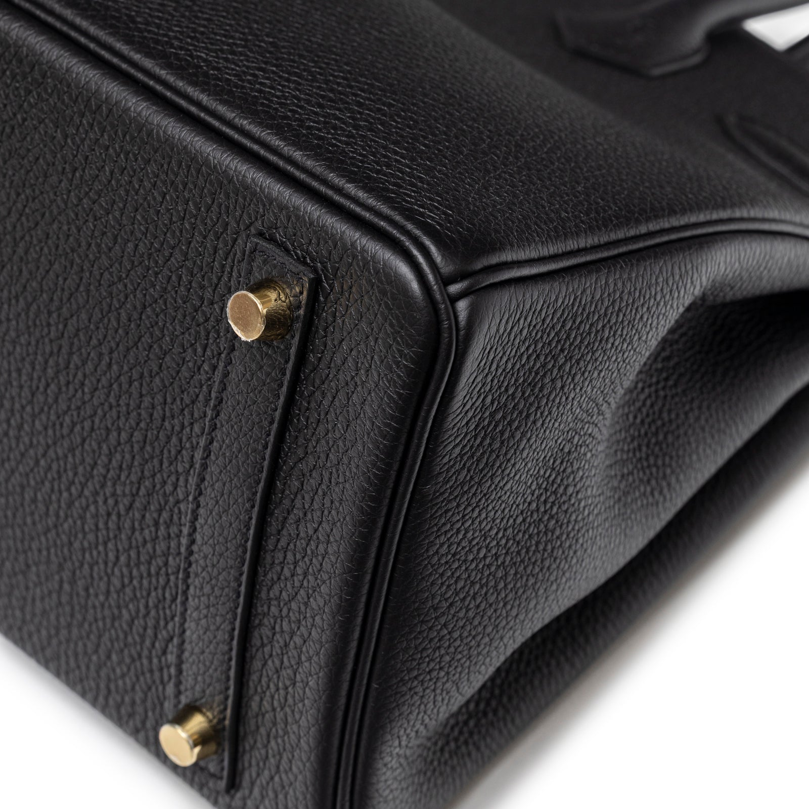 Close-up of base showing textured leather and gold hardware feet on Hermès Birkin 30 Black Togo Gold Hardware