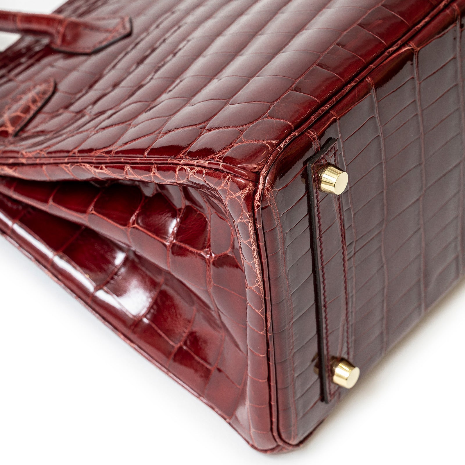 Close-up of the shiny burgundy Niloticus crocodile leather base with gold hardware on Hermès Birkin 30 bag