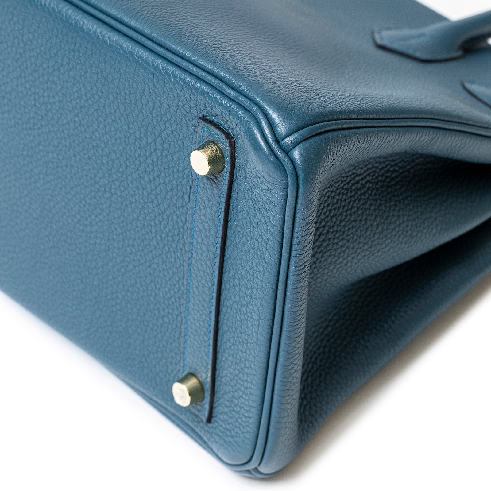 Close-up bottom corner of Hermès Birkin 30 Colvert Togo bag showing gold hardware and textured leather detail.