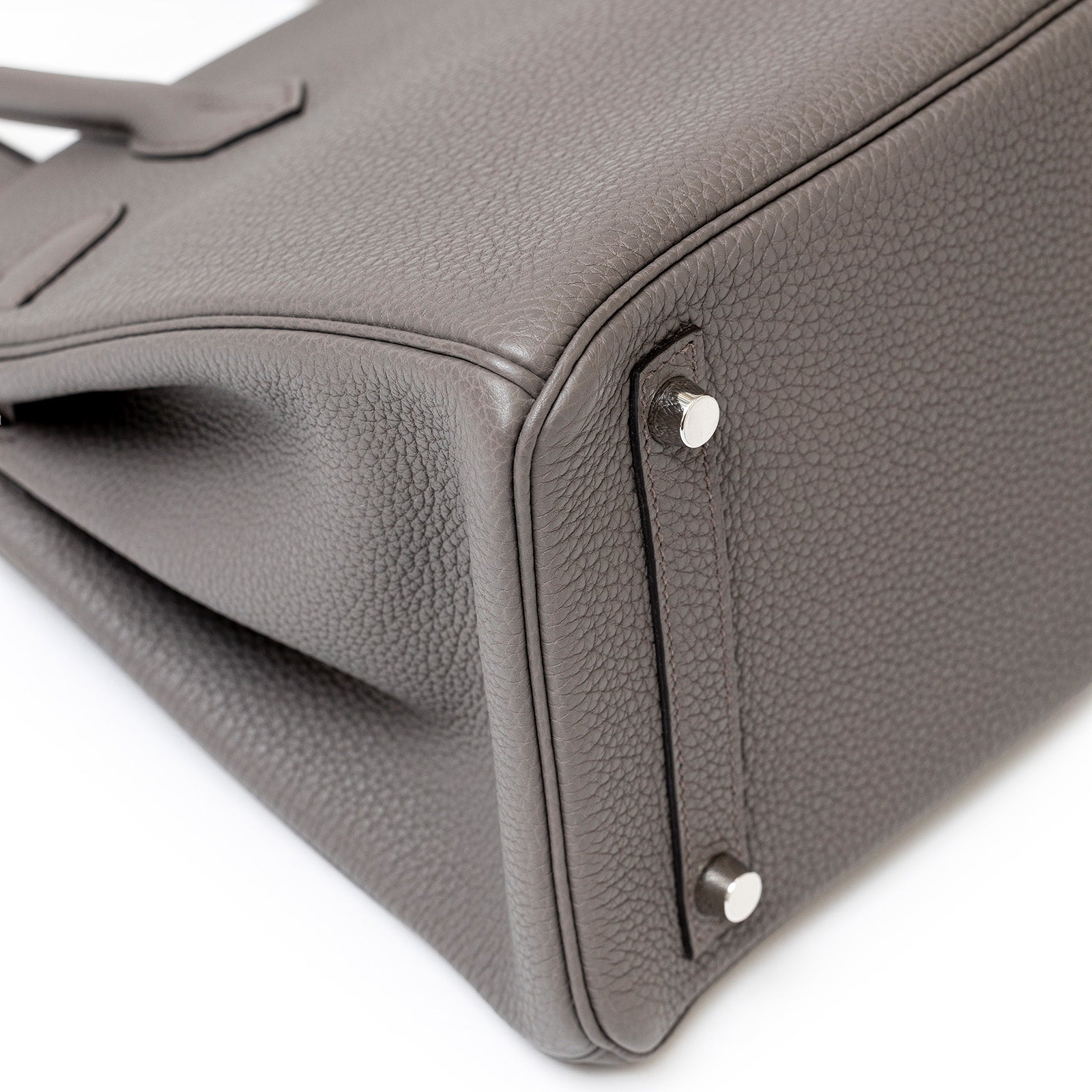 Close-up of bottom corner and palladium hardware on Hermès Birkin 30 Etain Togo leather handbag.