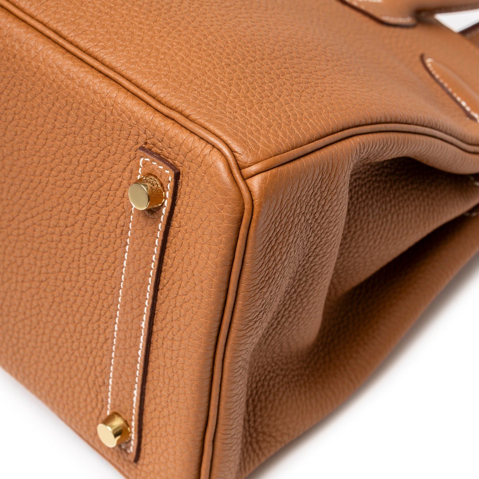 Close-up of the base of Hermès Birkin 30 Gold Togo Gold Hardware showing pebbled leather texture and protective metal feet.