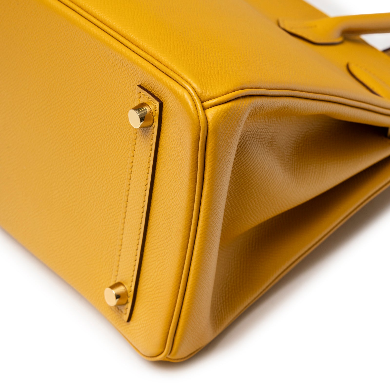 Close-up of base corner and gold feet on Hermès Birkin 30 Jaune Ambre Epsom Gold Hardware showing leather grain detail