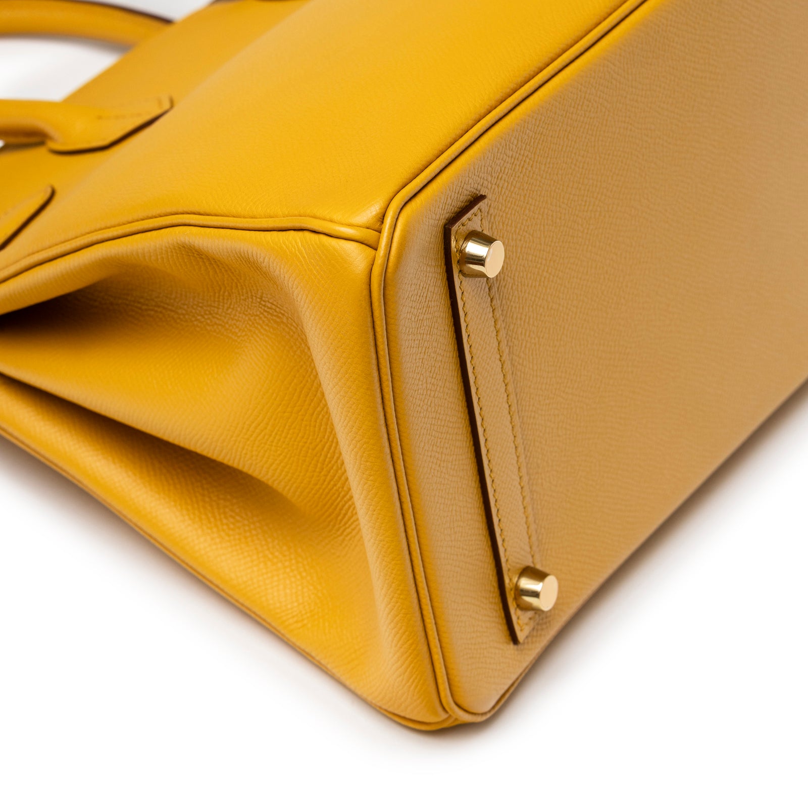 Close-up of base corner on Hermès Birkin 30 Jaune Ambre Epsom Gold Hardware showing grain texture and gold feet