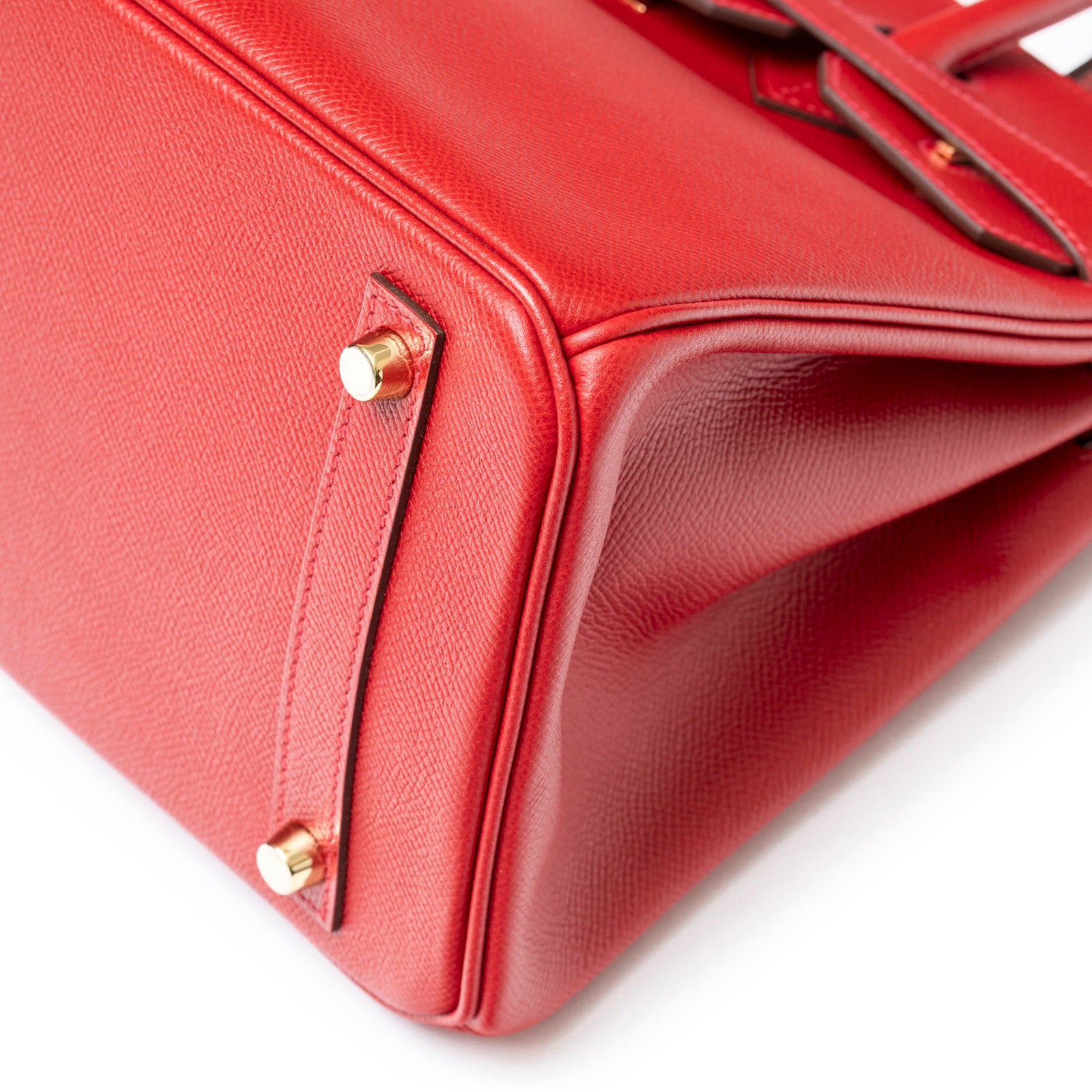 Close-up of the bottom corner showing Hermès Birkin 30 Rouge Casaque Epsom Gold Hardware texture and gold feet details