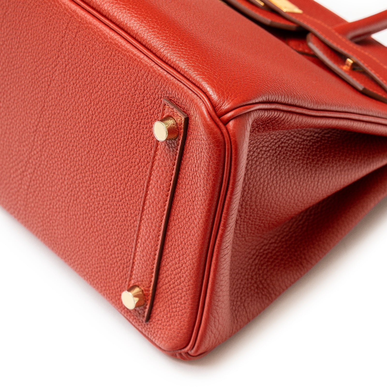 Close-up of the bottom corner of Hermès Birkin 30 Rouge Togo Gold Hardware showing texture and metal studs.
