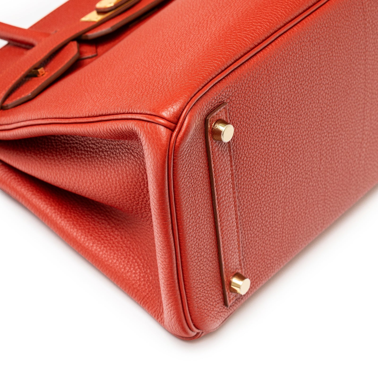 Close-up of base and gold hardware on Hermès Birkin 30 Rouge Togo Gold Hardware showing texture and stitching detail.