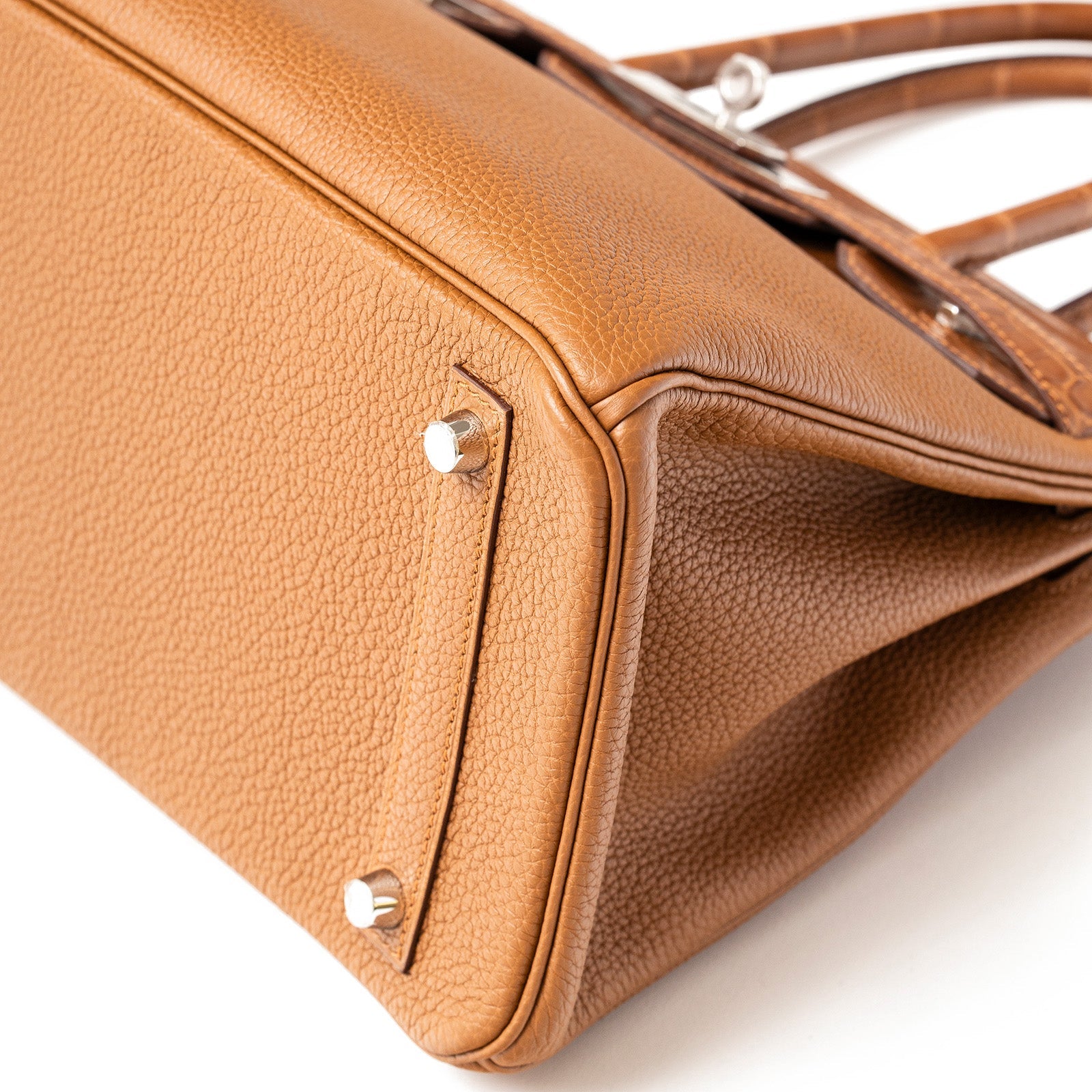 Close-up angled view of the Hermès Birkin 30 bottom corner showing gold palladium hardware and Togo leather texture