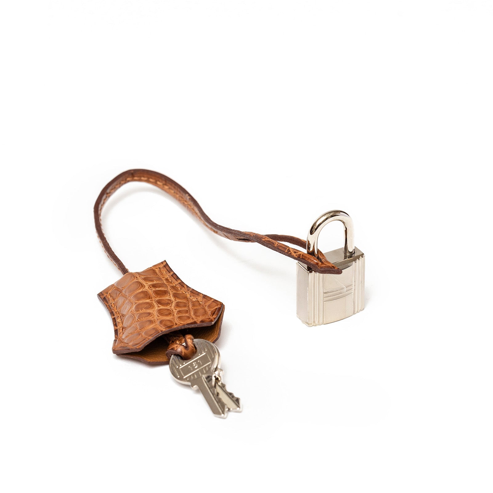 Close-up of matte alligator leather clochette with two keys and gold palladium padlock on white background