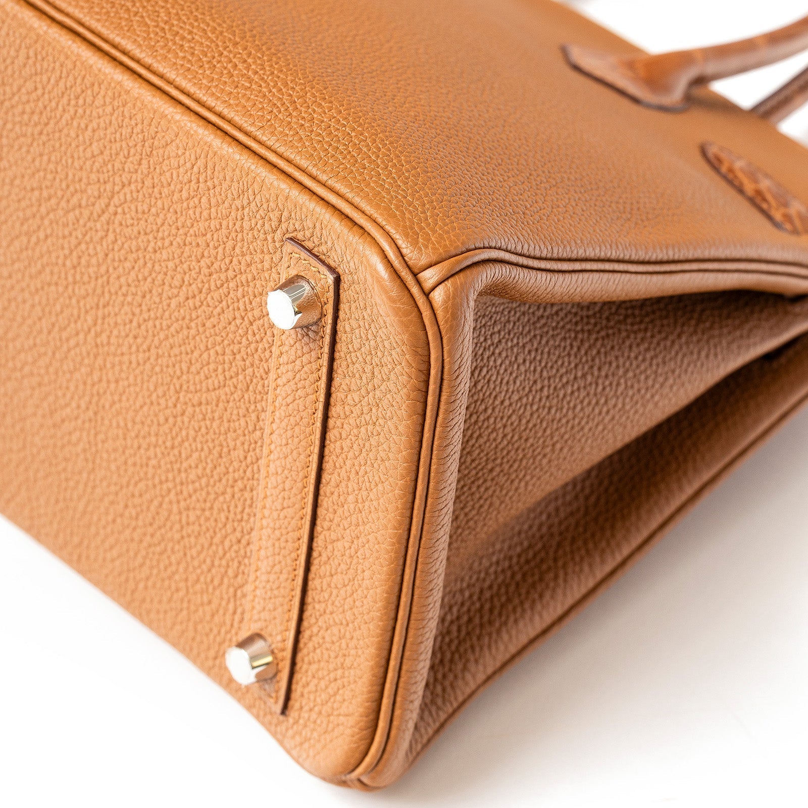 Close-up of Hermès Birkin 30 corner showing matte togo leather texture and gold palladium hardware feet detail.