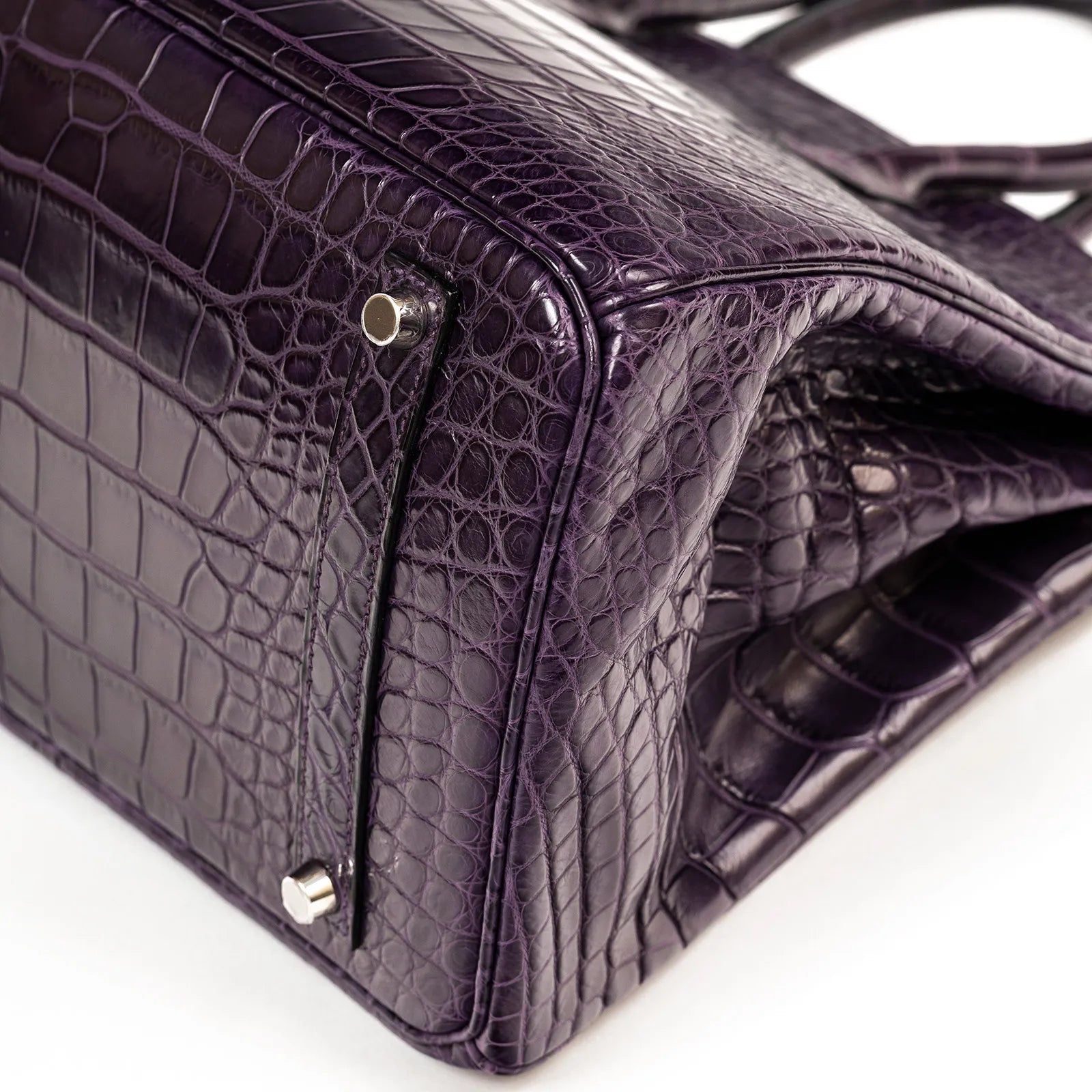 Close-up of Hermès Birkin 35 Amethyste Matte Alligator showing palladium hardware and textured leather corner detail.
