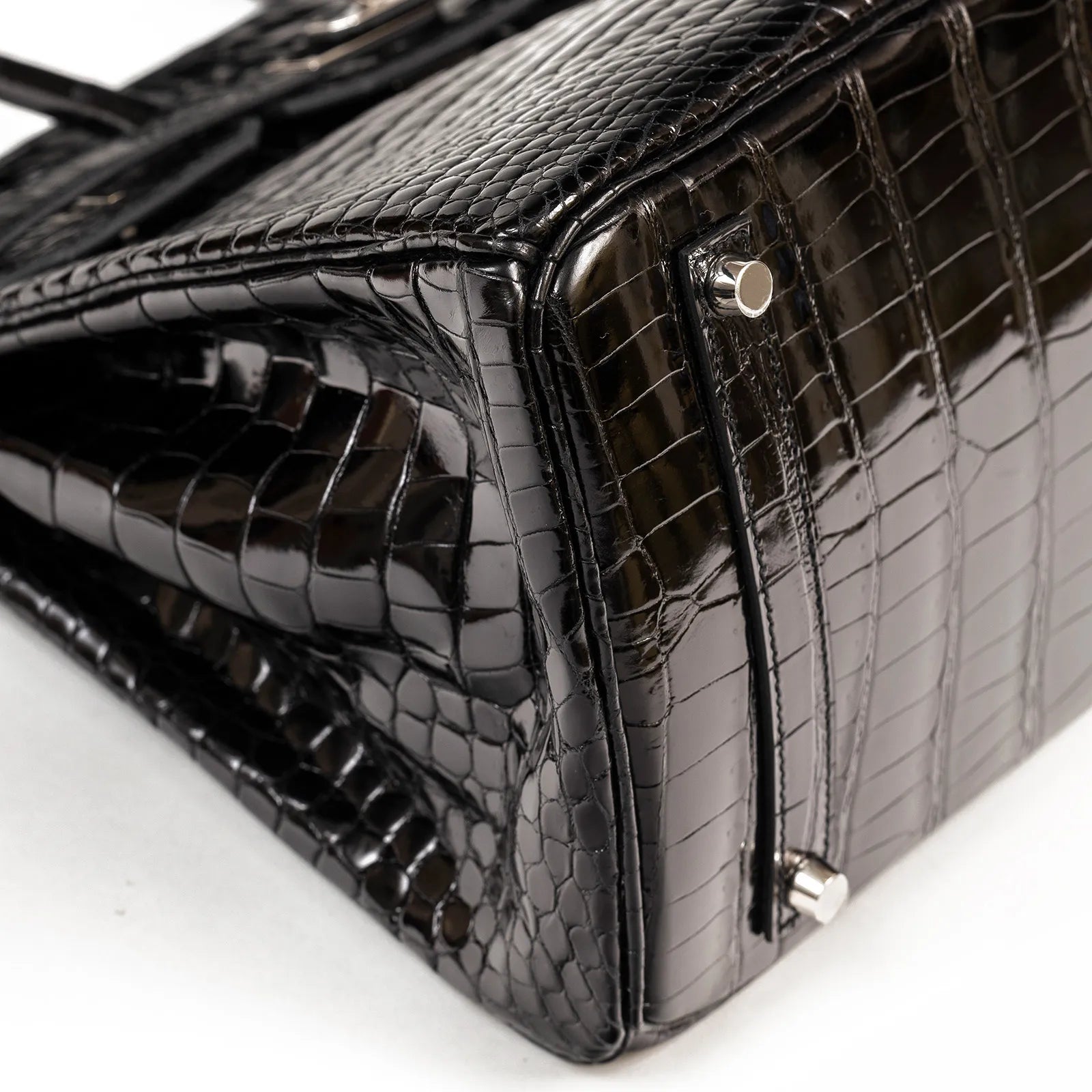 Close-up of corner and palladium feet on Hermès Birkin 35 Black Shiny Porosus with detailed crocodile texture.
