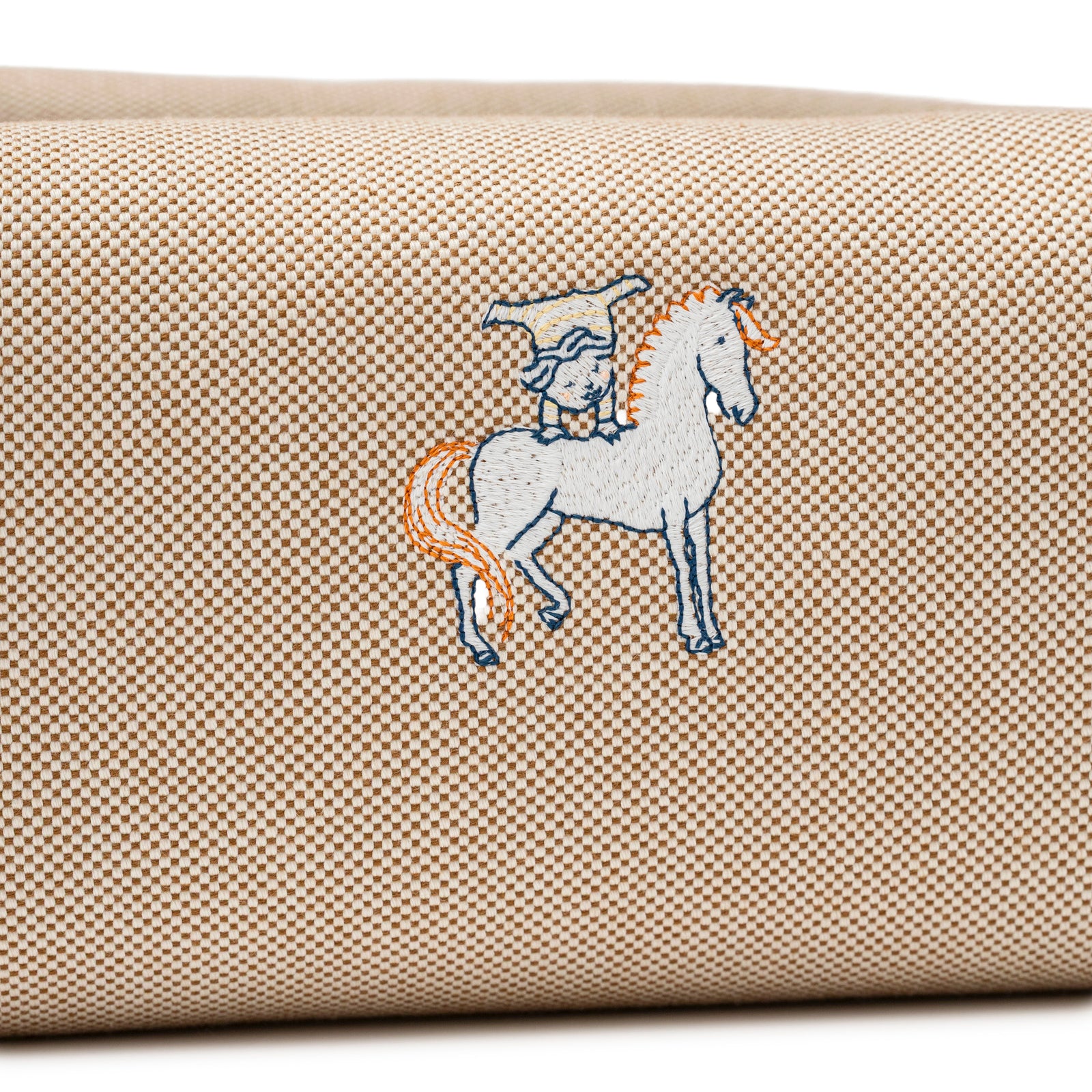 Close-up of the Hermès Bride-A-Brac Cabriole Case GM Toile Biscuit fabric showing detailed horse and rider embroidery on beige checkered texture