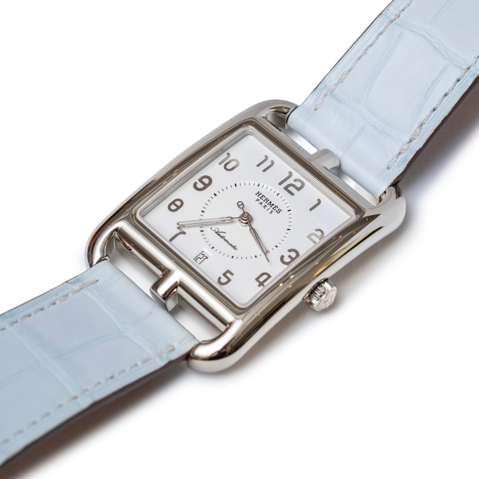 Angled close-up of Hermès Cape Cod Automatic Watch Large Model Blue Brume Matte Alligator showing silver case and light blue strap details