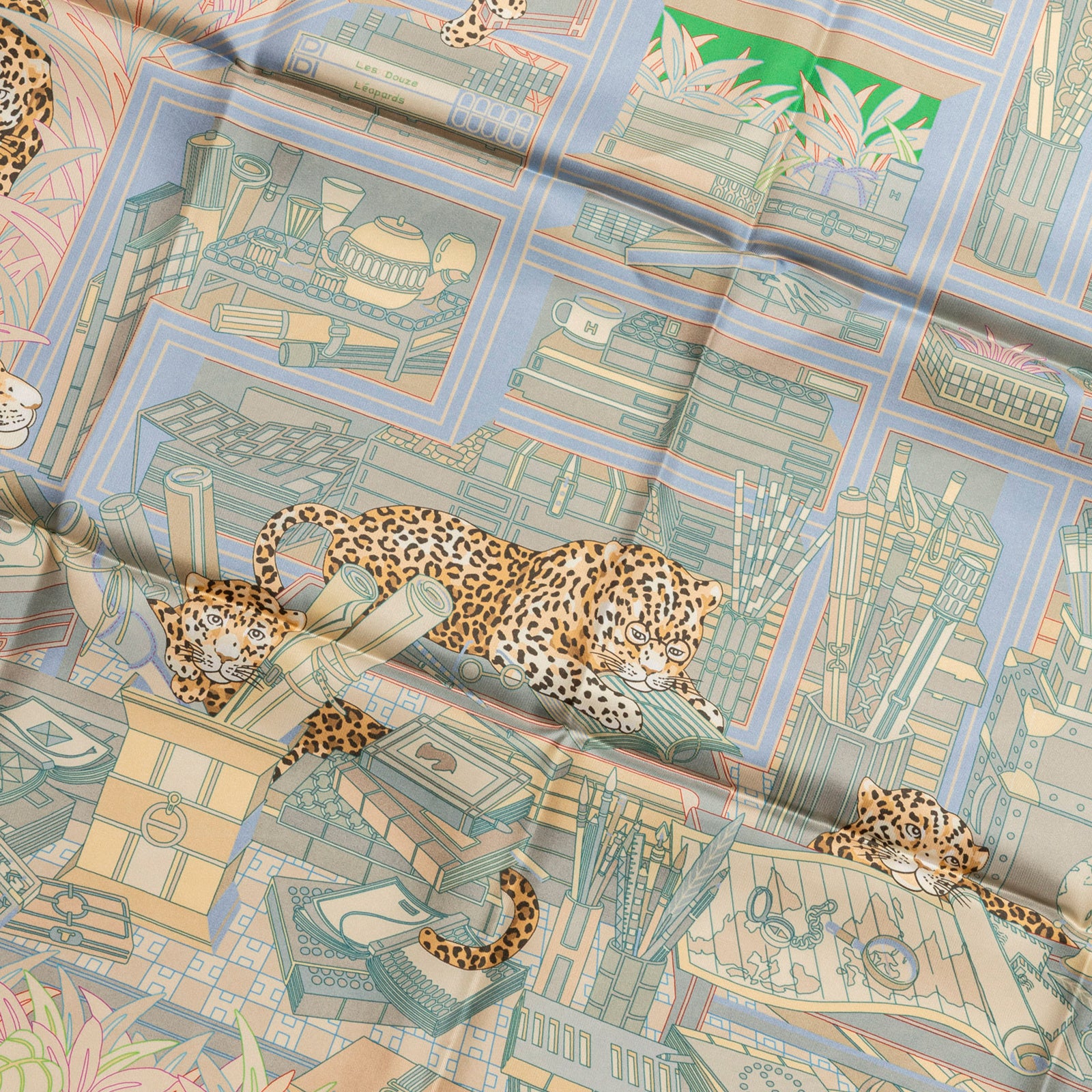 Close-up angled view of Hermès Carre 90 Double Face Les Douze Leopards Blue Beige Jaune silk scarf with detailed leopard illustrations.