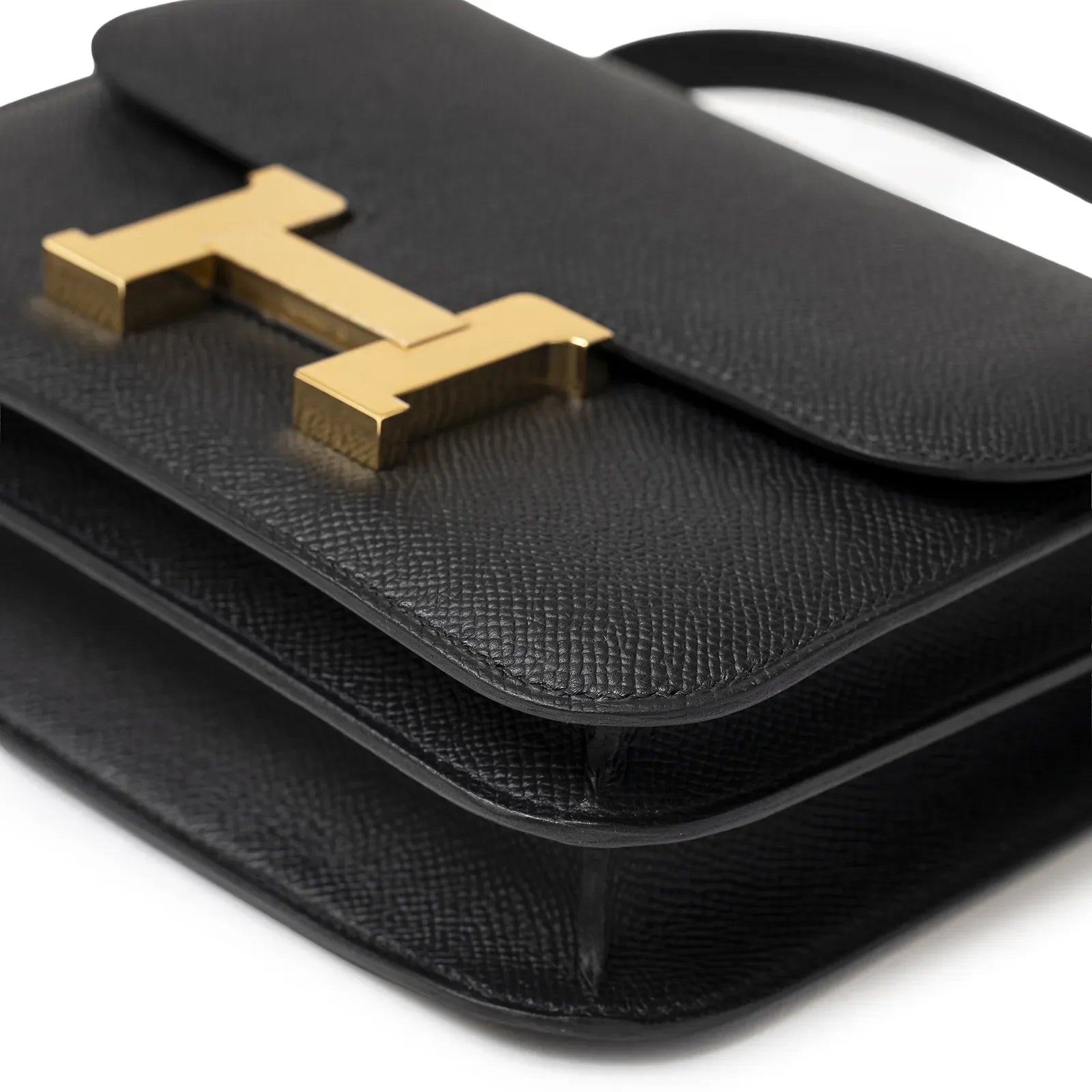 Close-up angled shot of Hermès Mini Constance 18 Black Epsom Gold Hardware showing textured leather and gold clasp detail