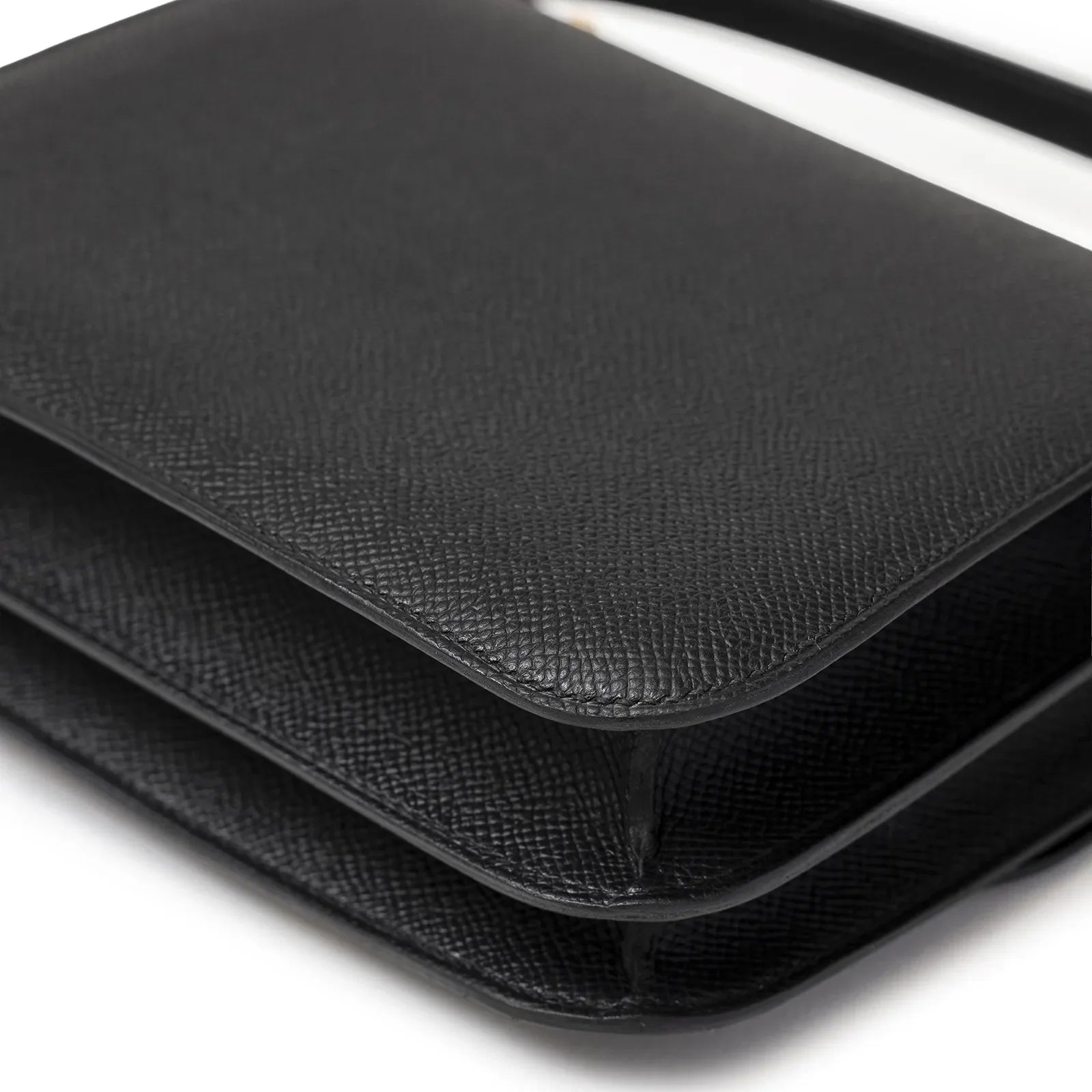 Close-up angled view of Hermès Mini Constance 18 Black Epsom Gold Hardware showing textured leather edges and flap details