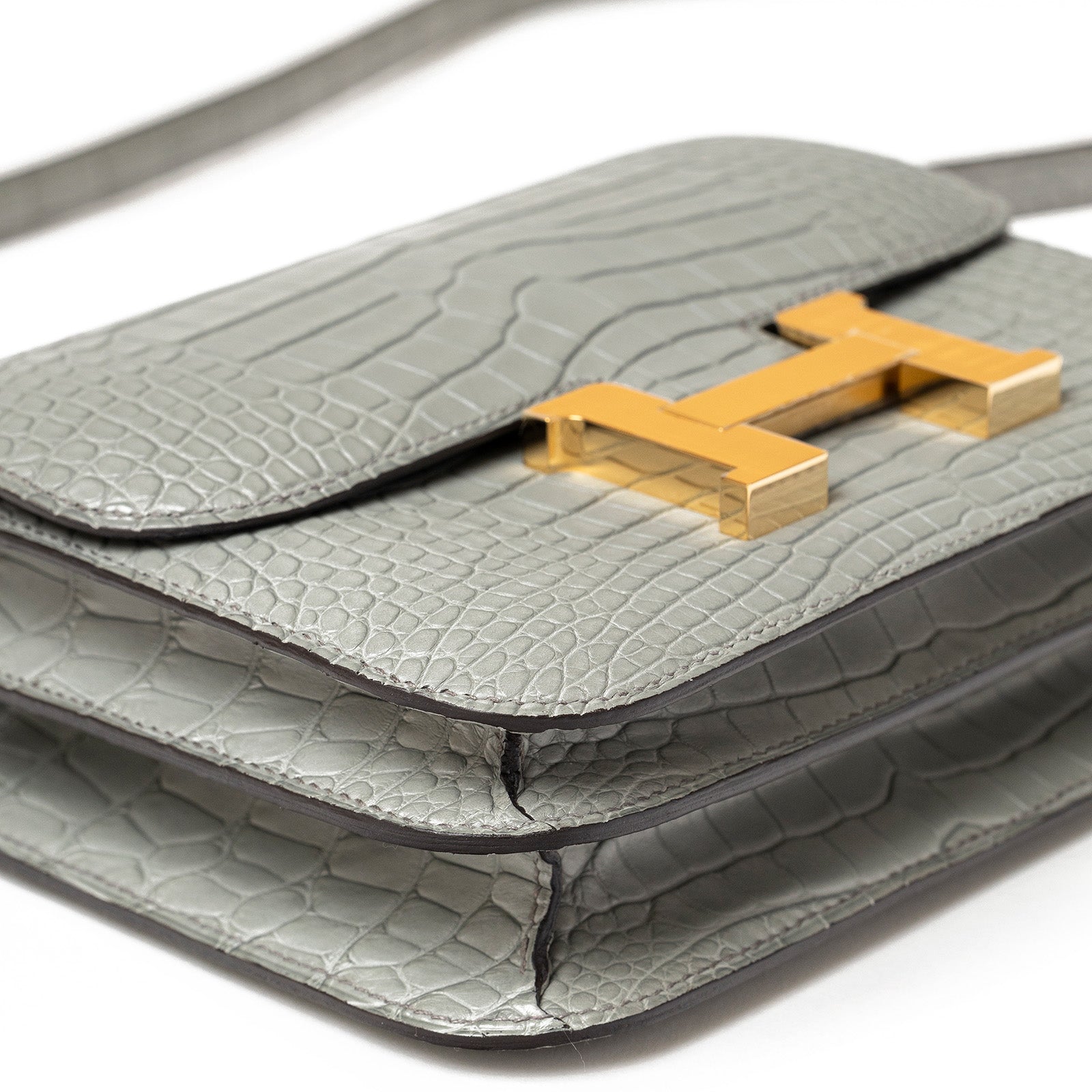 Close-up of Hermès Mini Constance 18 Gris Ciment Matte Alligator Gold Hardware showing texture and clasp details