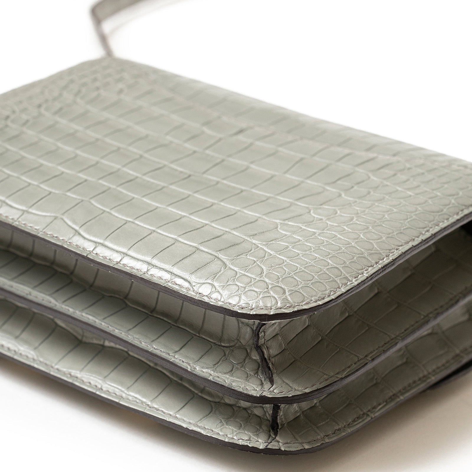 Close-up angled shot of Hermès Mini Constance 18 Gris Ciment Matte Alligator Gold Hardware showing texture and stitching detail