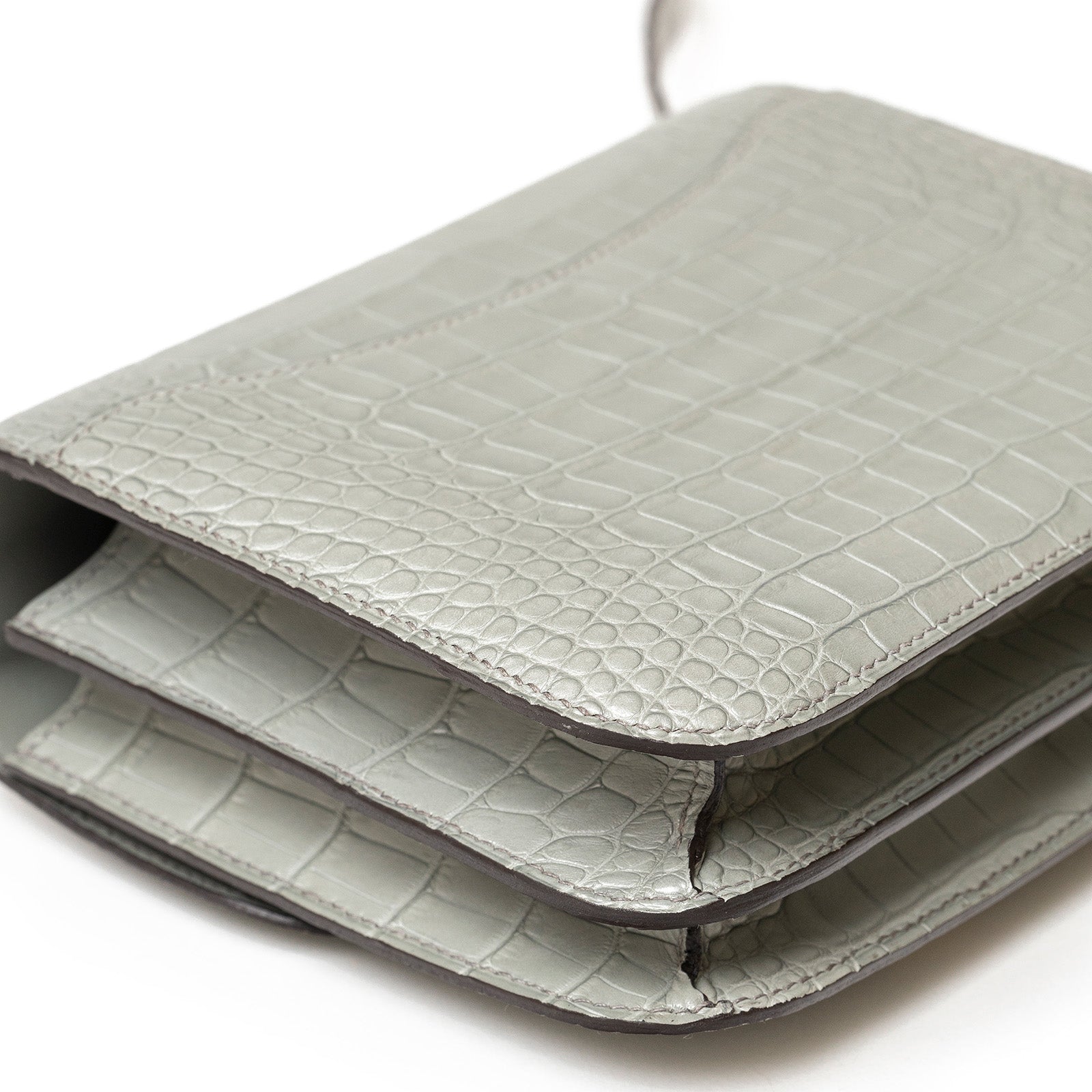 Close-up angled view of Hermès Mini Constance 18 Gris Ciment Matte Alligator Gold Hardware showing texture and stitching details