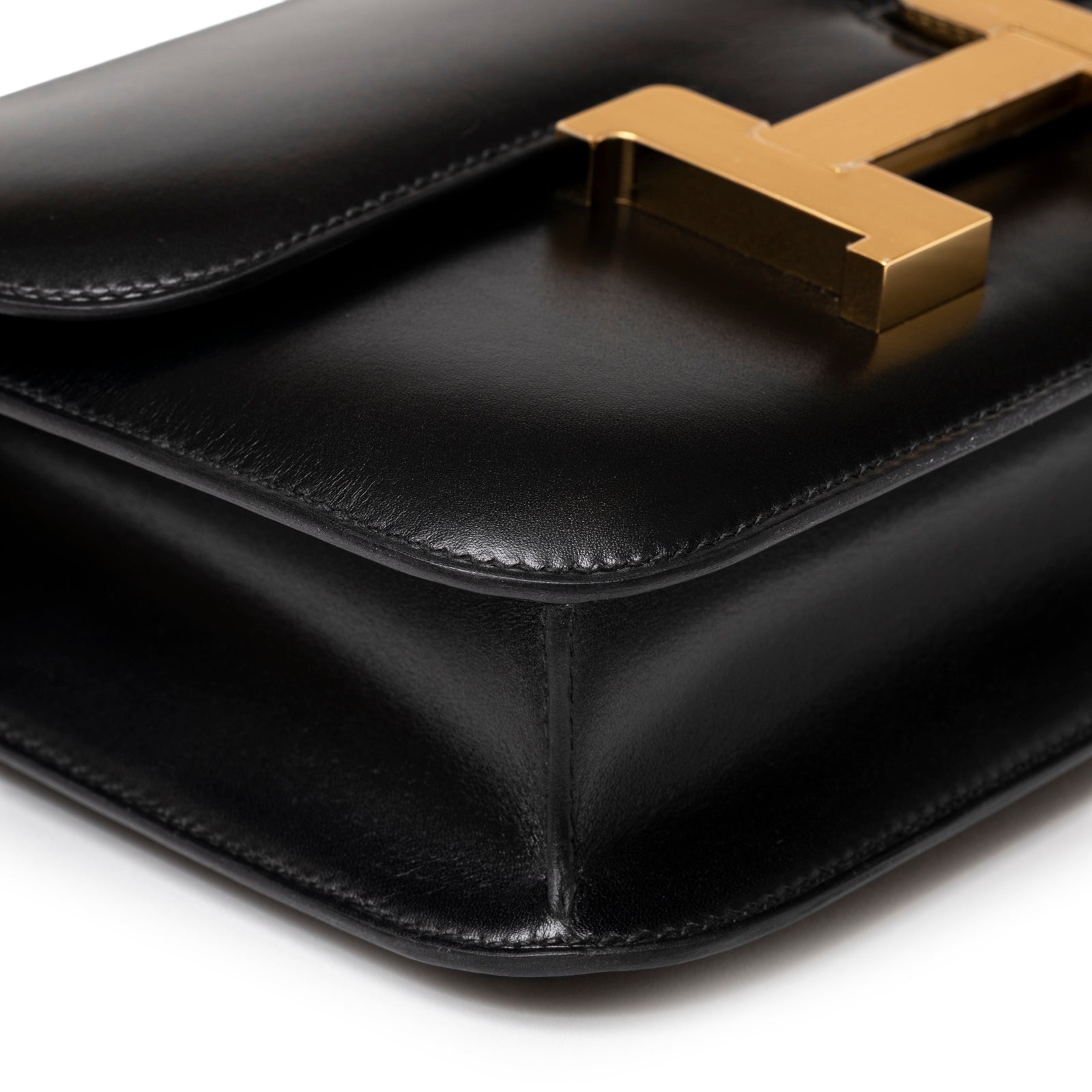 Close-up of corner and flap edge on Hermès Constance 24 Black Box Gold Hardware showing sleek leather and gold clasp detail