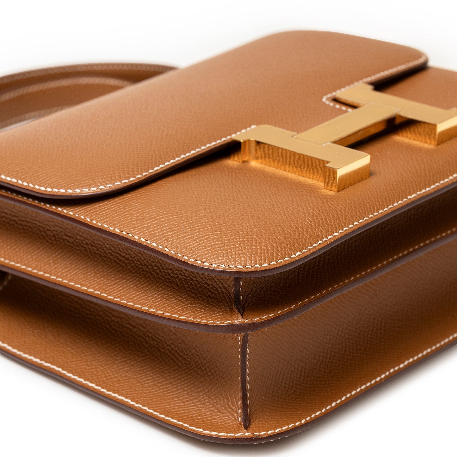 Close-up angled shot of Hermès Constance 24 Gold Epsom Gold Hardware showing textured leather and gold clasp detail