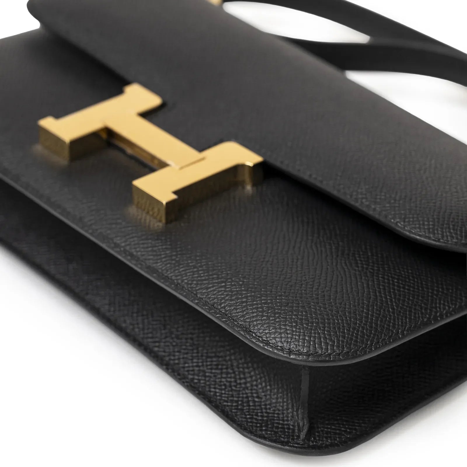 Close-up angled shot of Hermès Constance Elan Black Epsom Gold Hardware showing textured leather and gold clasp detail
